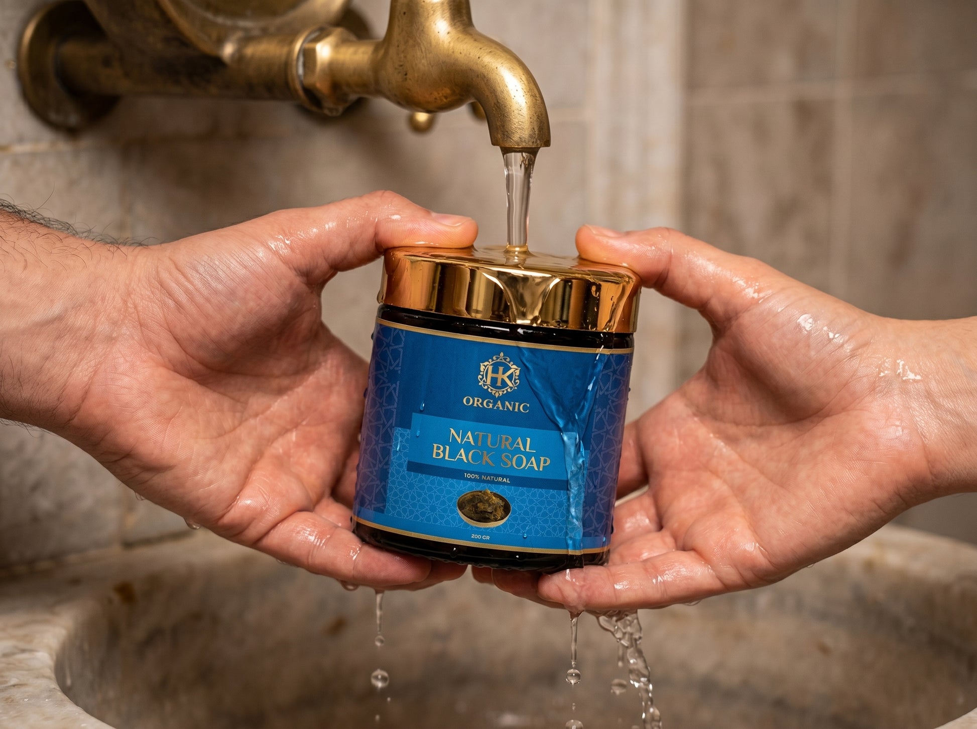 Person pouring water from a blue jar labeled 'Organic Natural Black Soap' into a sink.