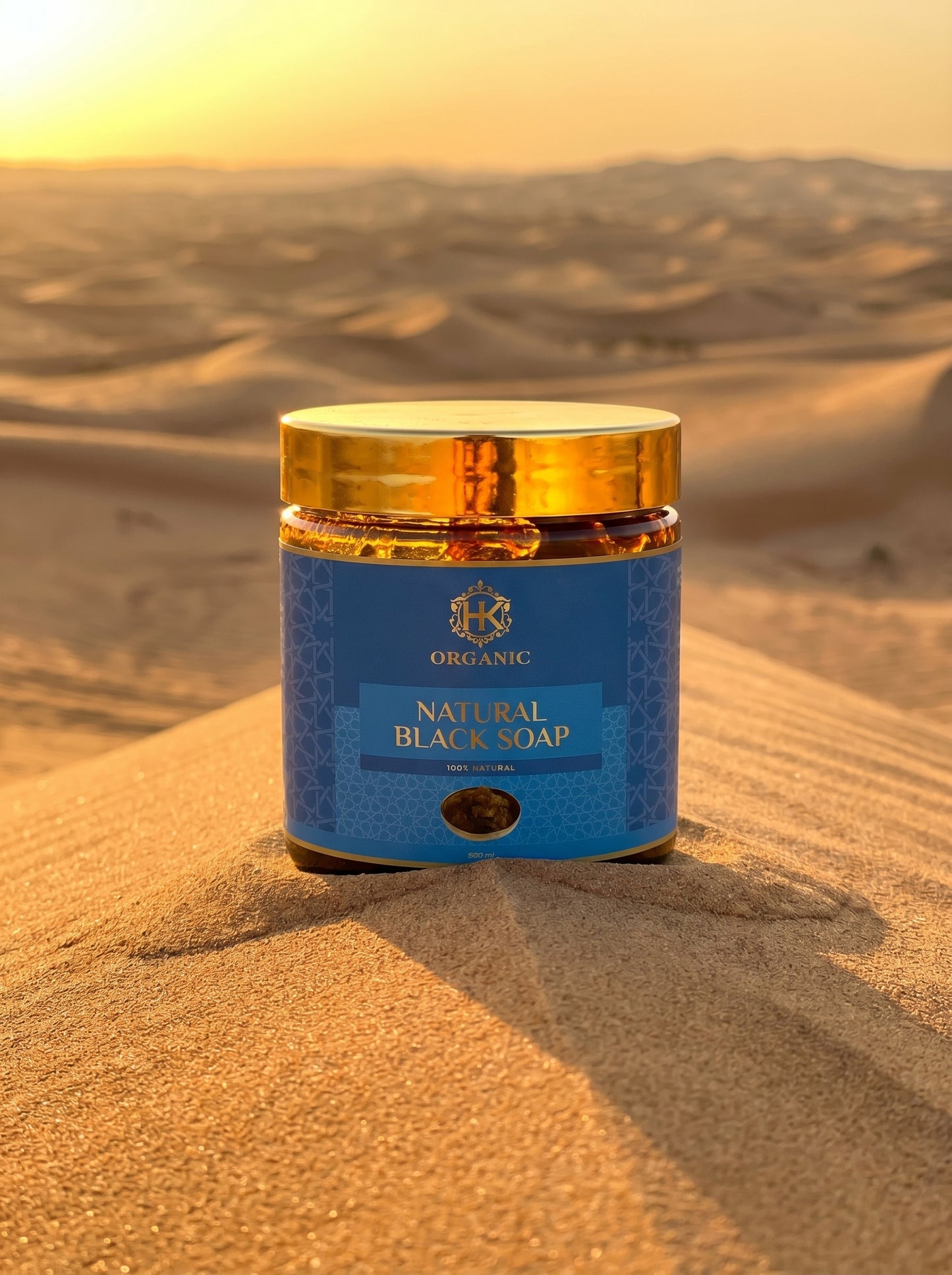 Jar of natural black soap on a sand dune with a sunset in the background