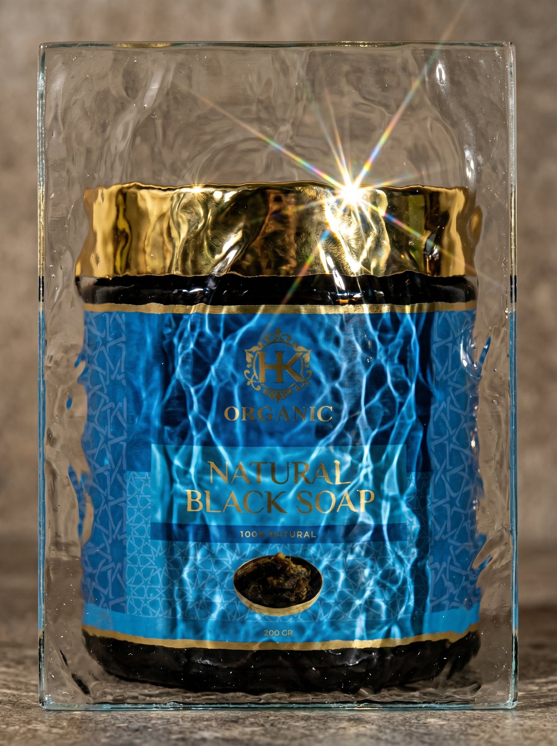 Jar of natural black soap with blue label and gold accents on a reflective surface.