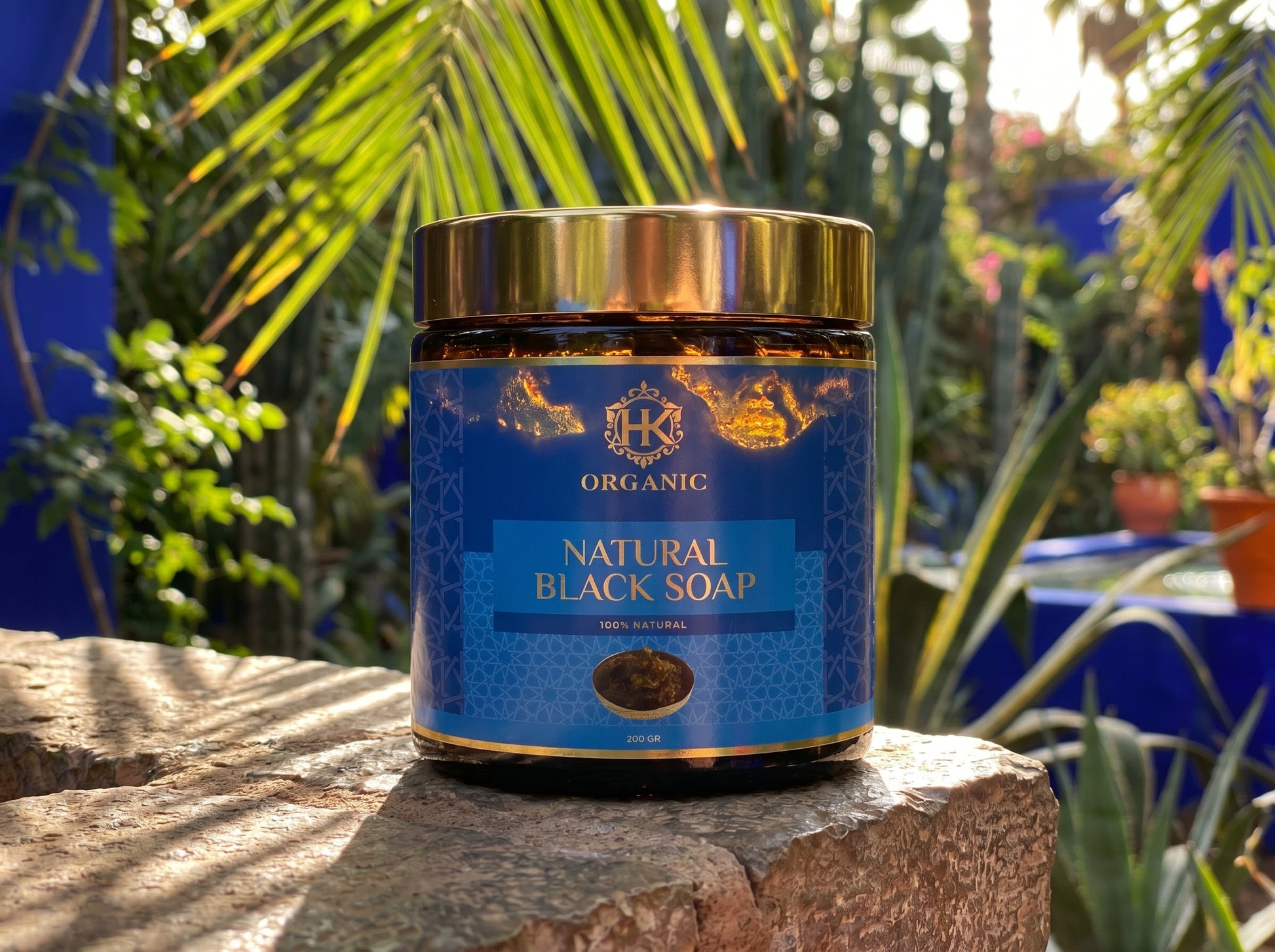 Jar of natural black soap on a stone surface with plants in the background
