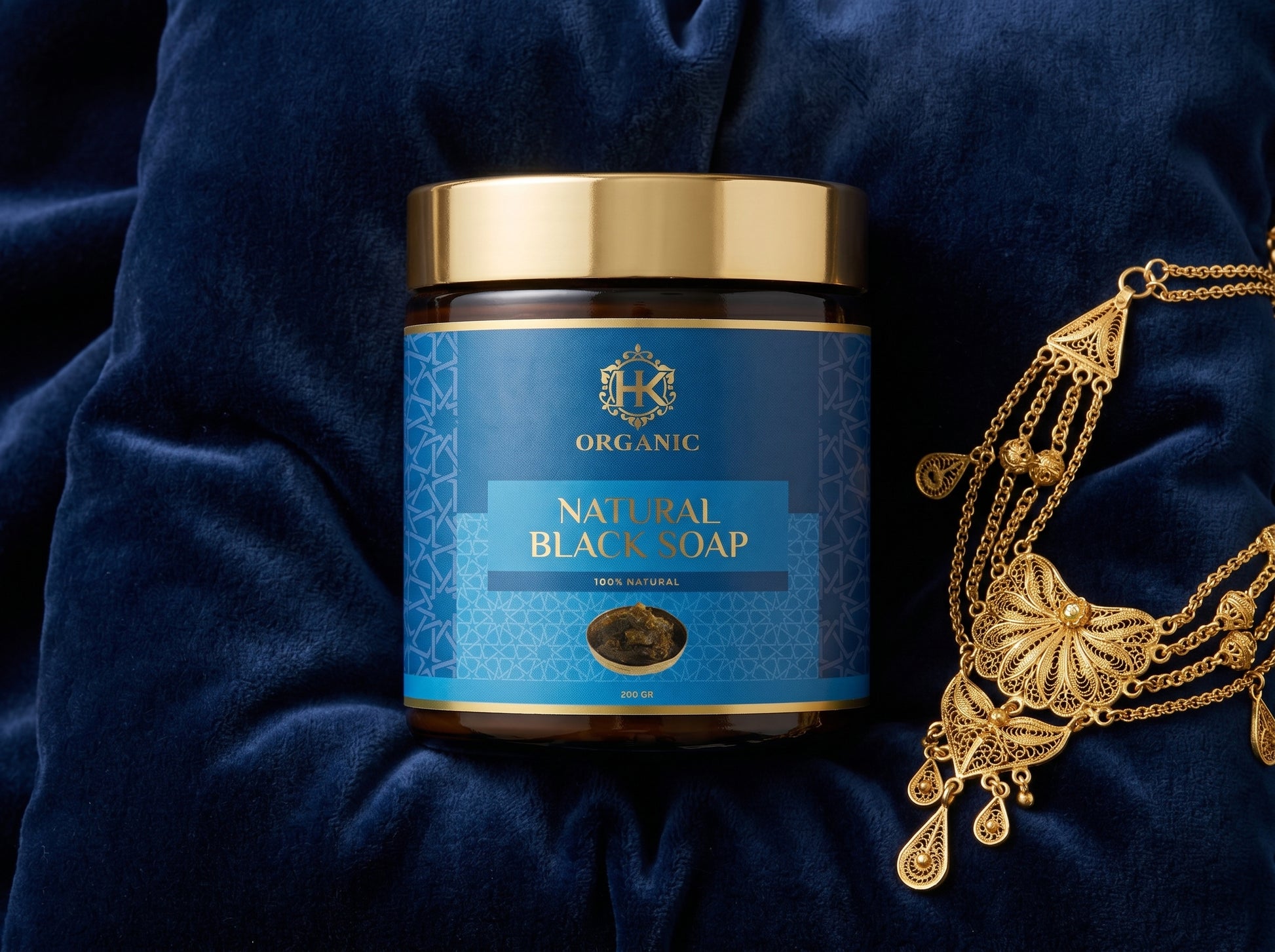 Jar of natural black soap with a blue label on a dark fabric background