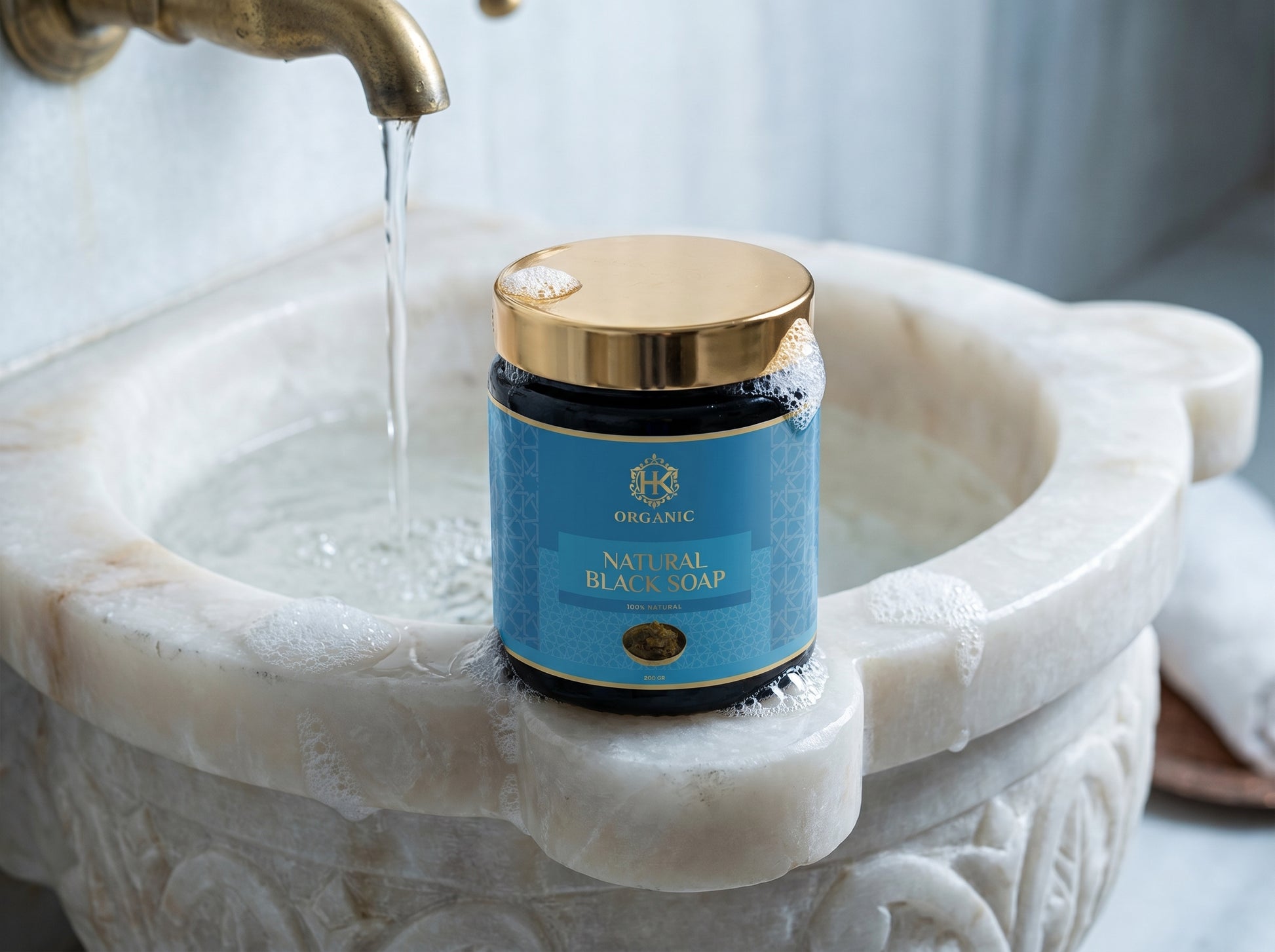 Jar of natural beach soap on a marble sink with running water