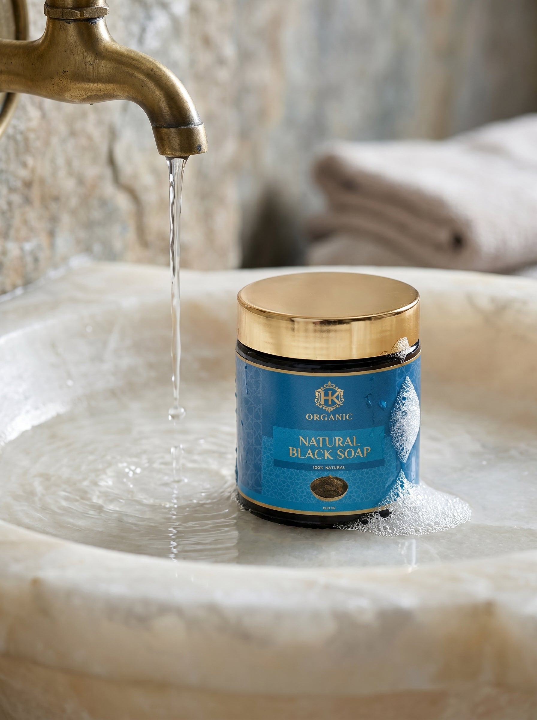 Jar of natural black soap on a sink with water flowing