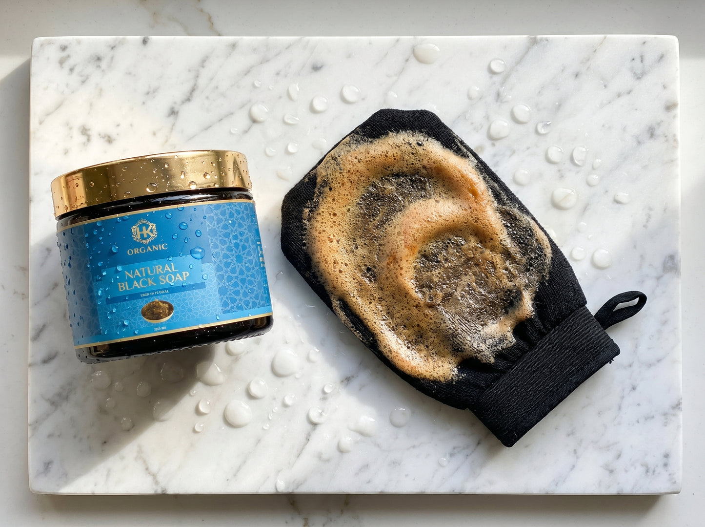 Jar of black soap and a black soap bar on a marble surface