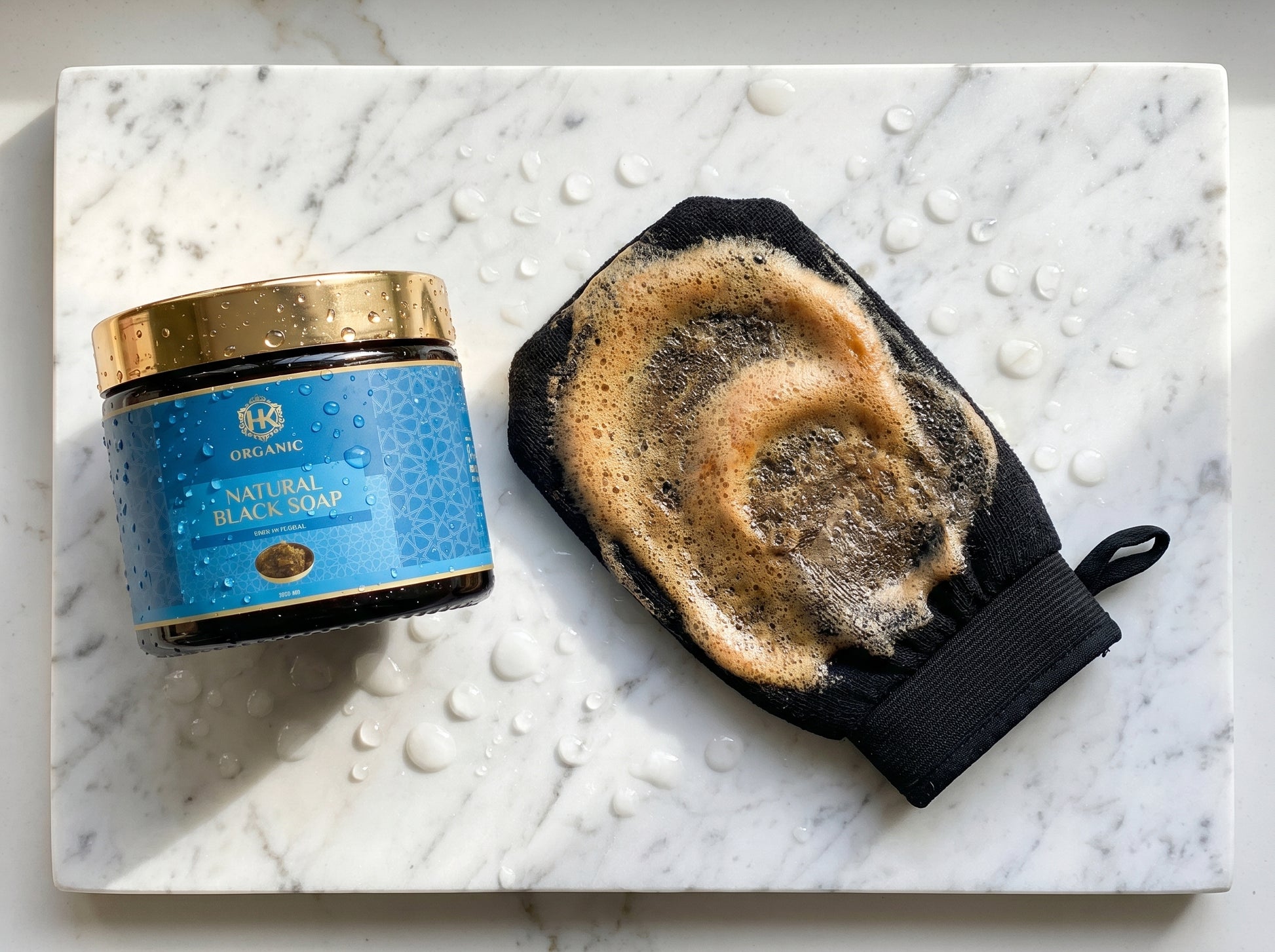 Jar of black soap and a black soap bar on a marble surface