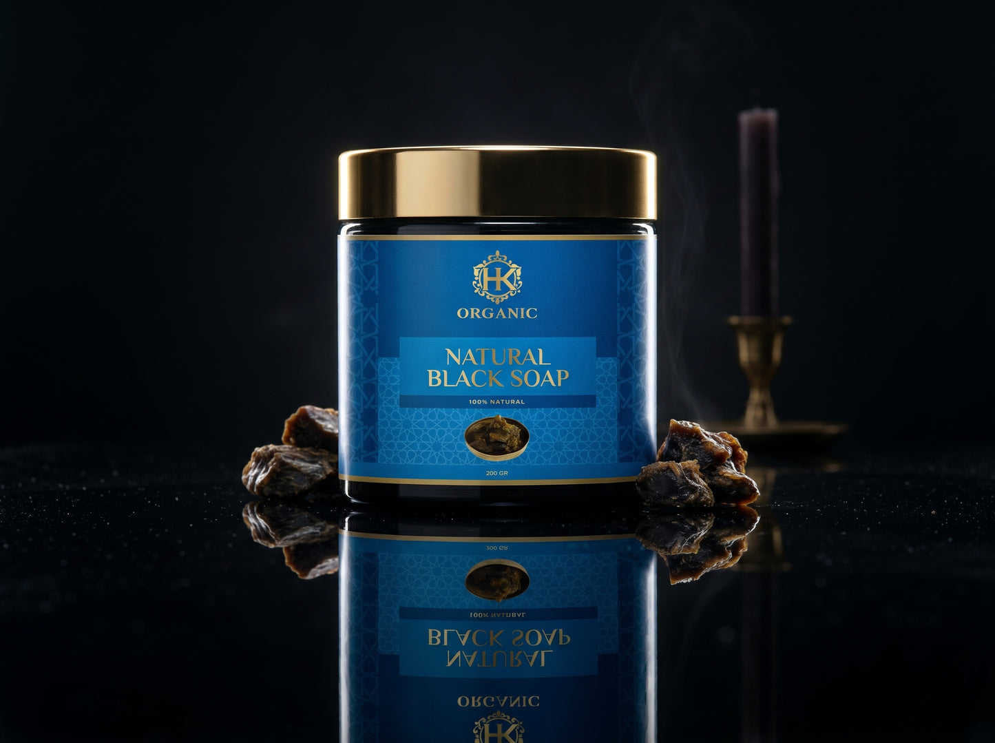 Jar of natural black soap with a blue label on a reflective surface.