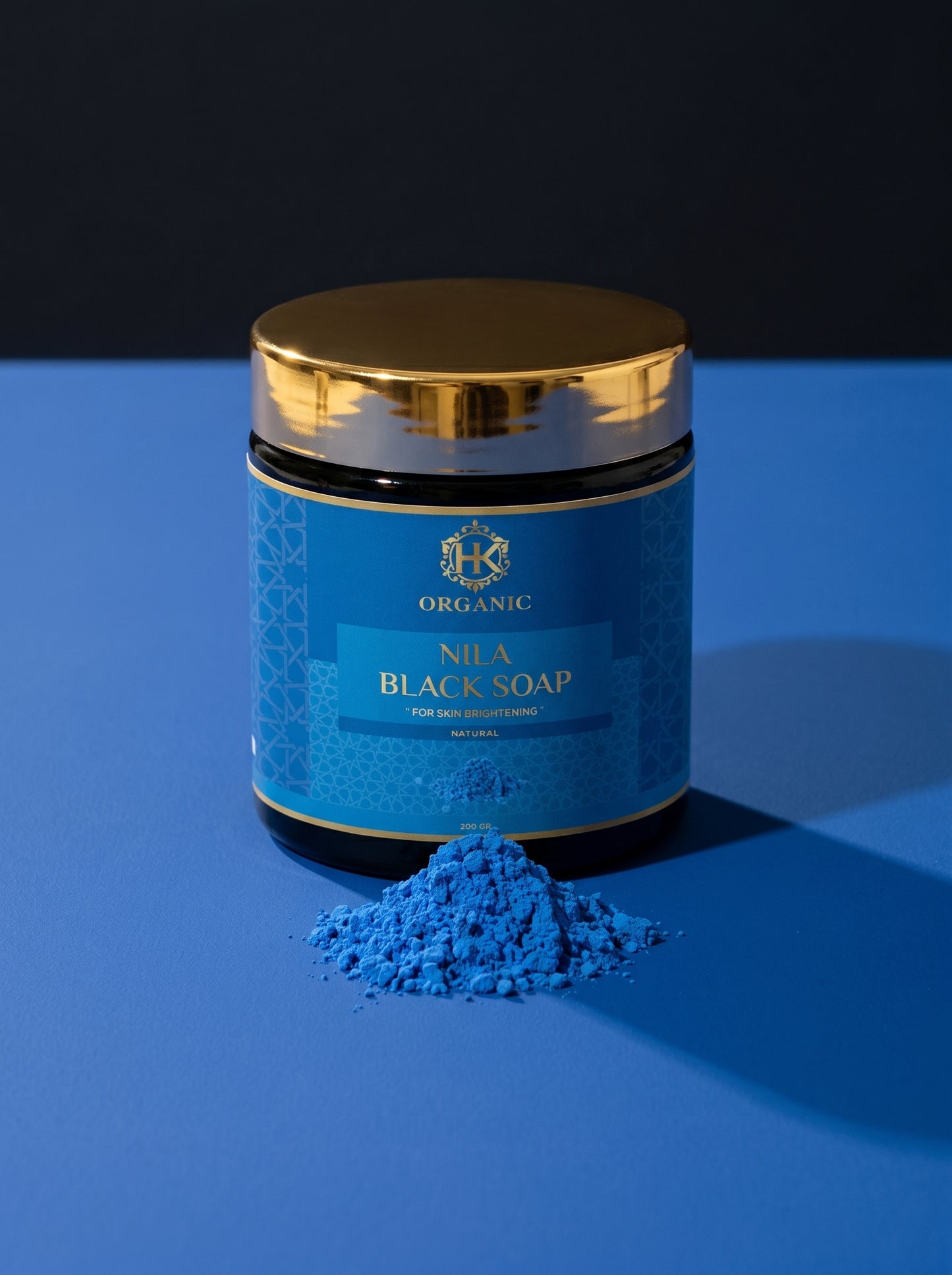 Blue container of Nila Black Soap with gold lid on a blue background