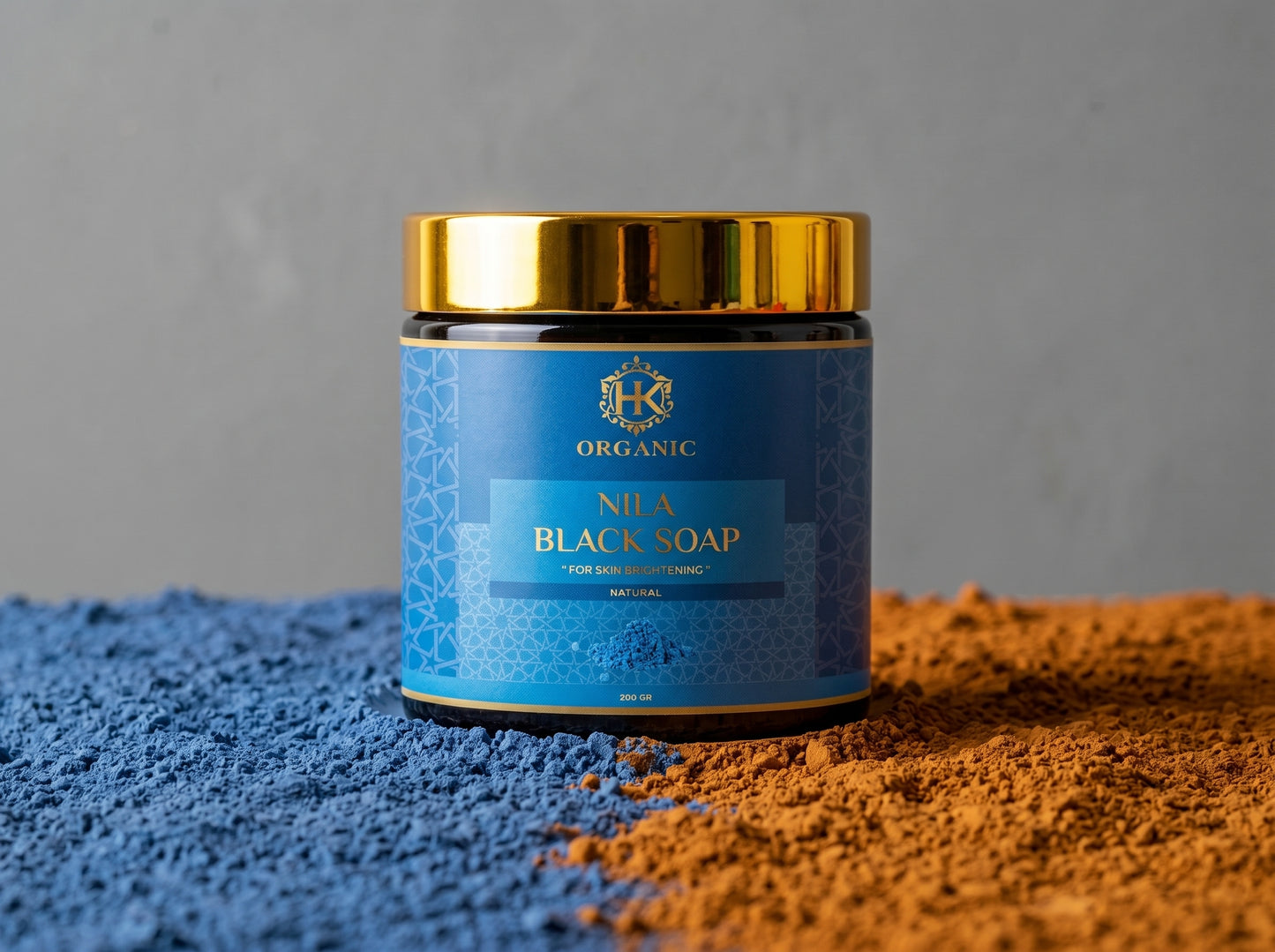 Jar of Nuba Black Soap with blue label and gold lid on a textured surface.