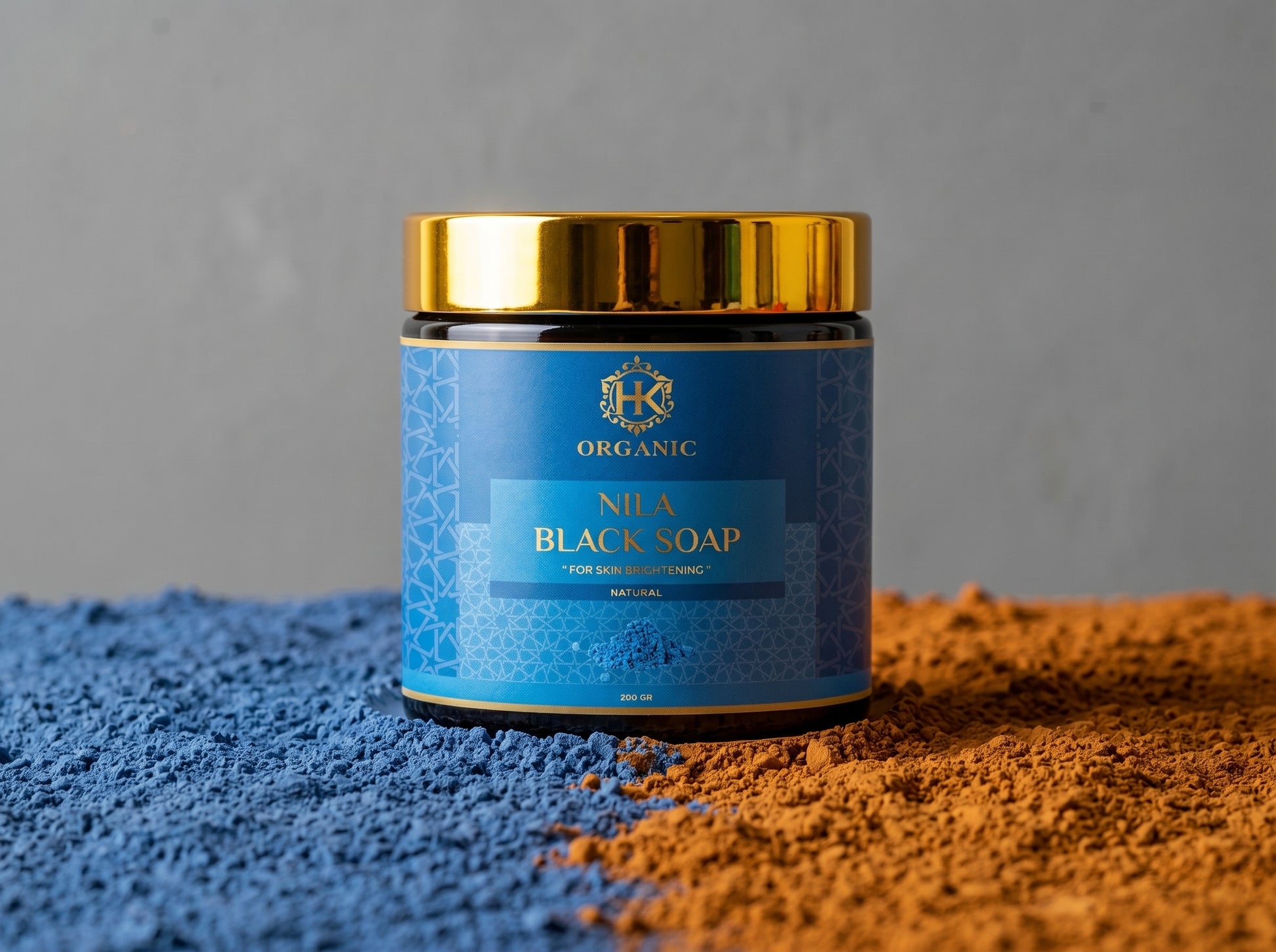 Jar of Nuba Black Soap with blue label and gold lid on a textured surface.