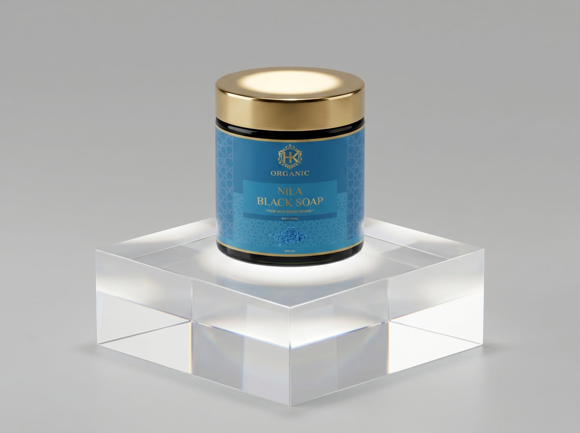 Jar of Nila Black Soap with gold lid on a clear stand against a gray background