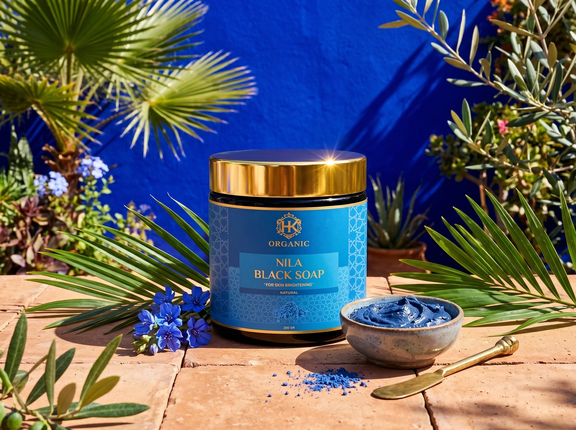 Nila Black Soap container with a blue label and gold lid on a wooden surface with greenery.