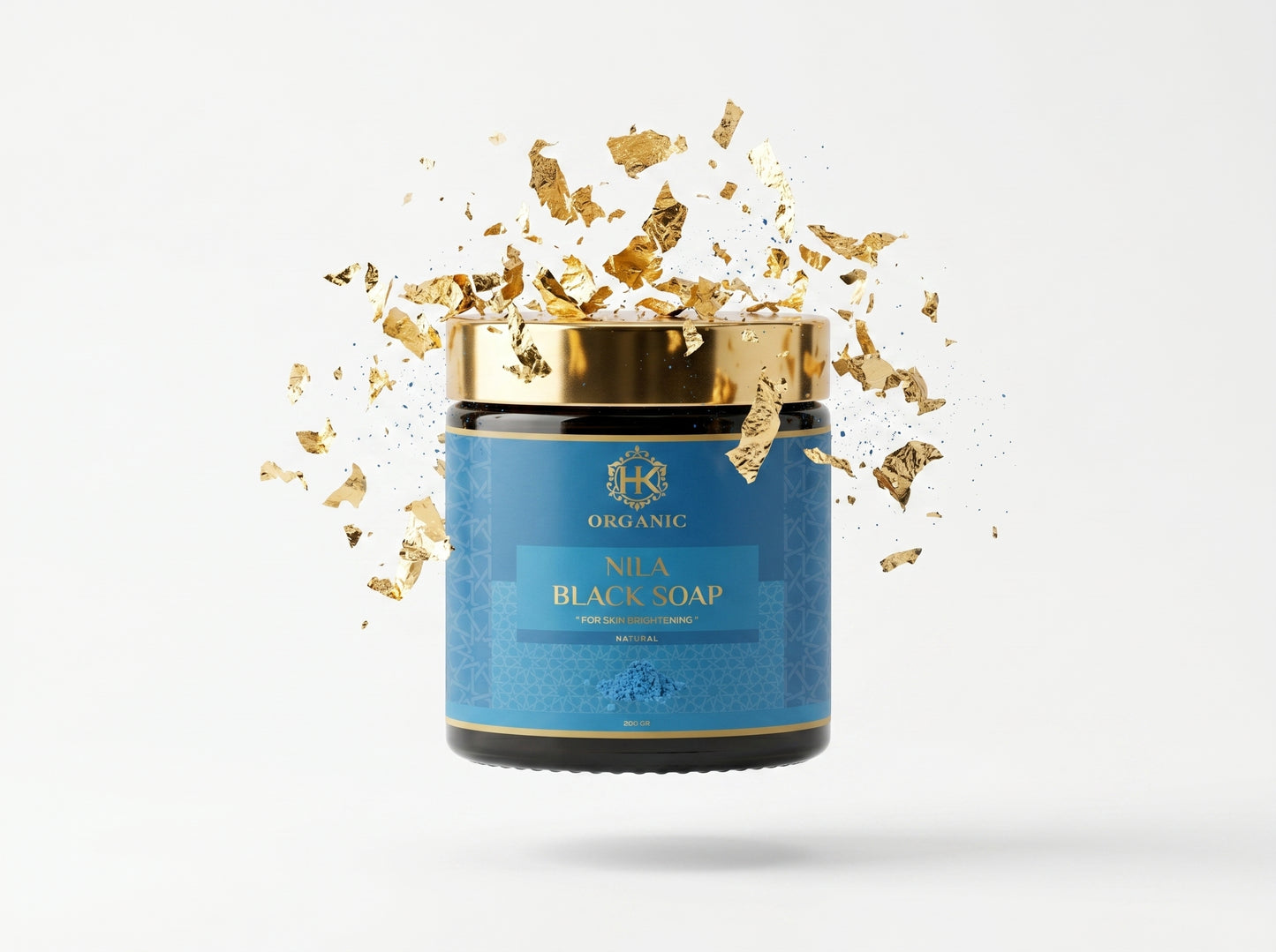 Blue jar of Nila Black Soap with gold flakes on a white background