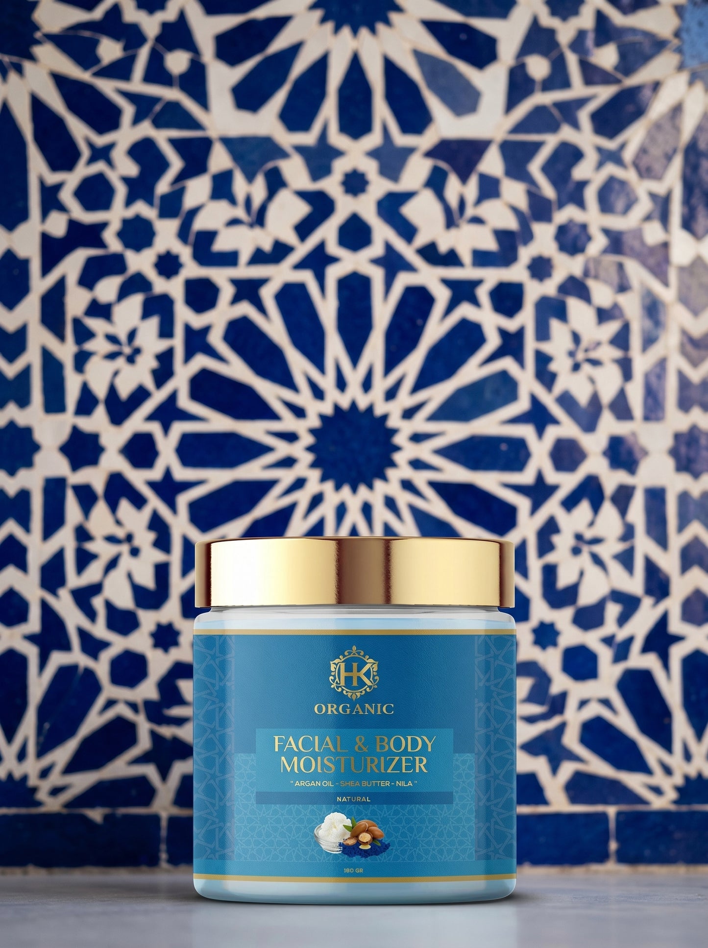 Facial and body moisturizer jar with gold lid against a blue and white patterned wall.