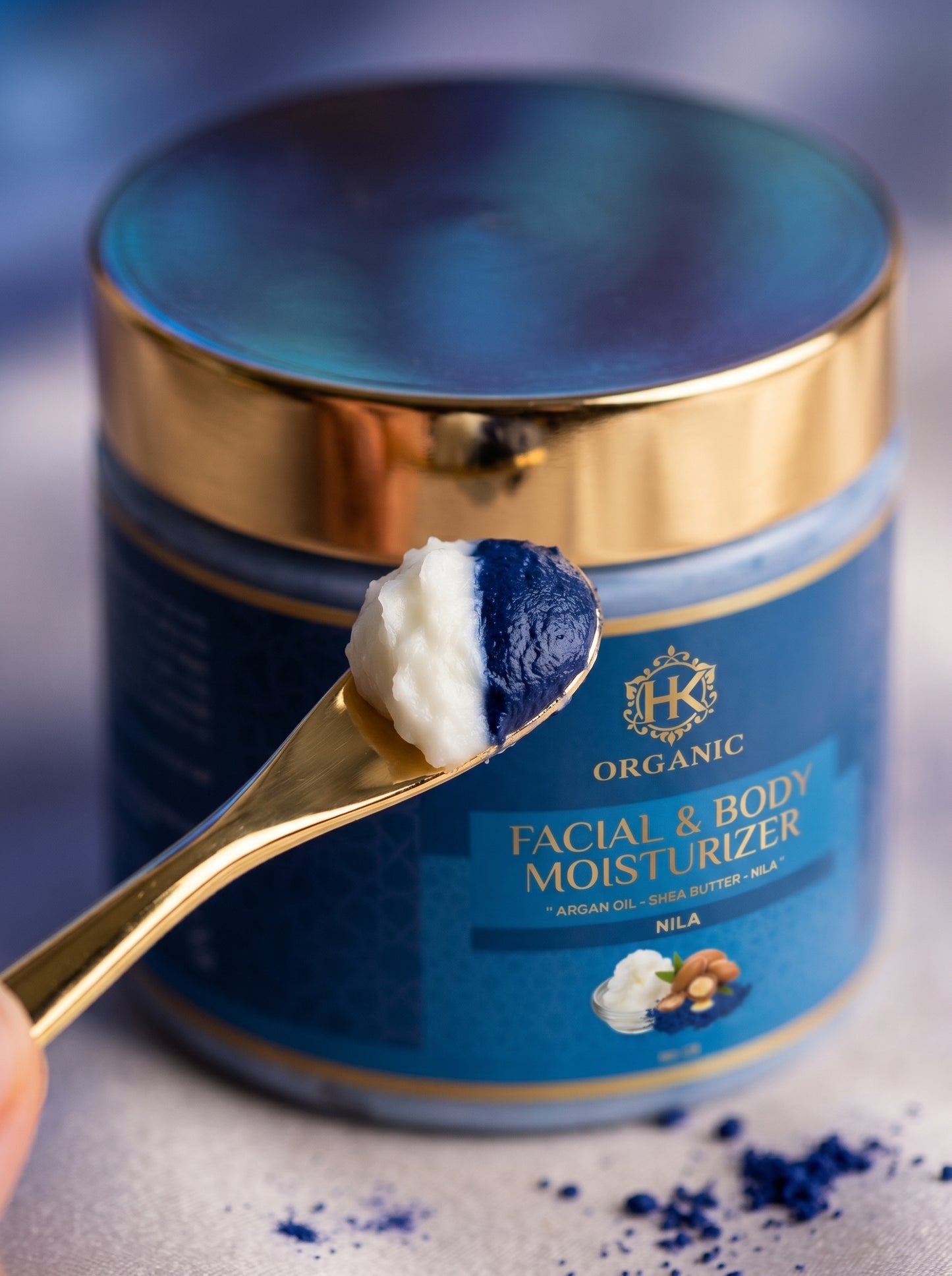 Blue jar of facial and body moisturizer with a spoonful of cream on a gray background
