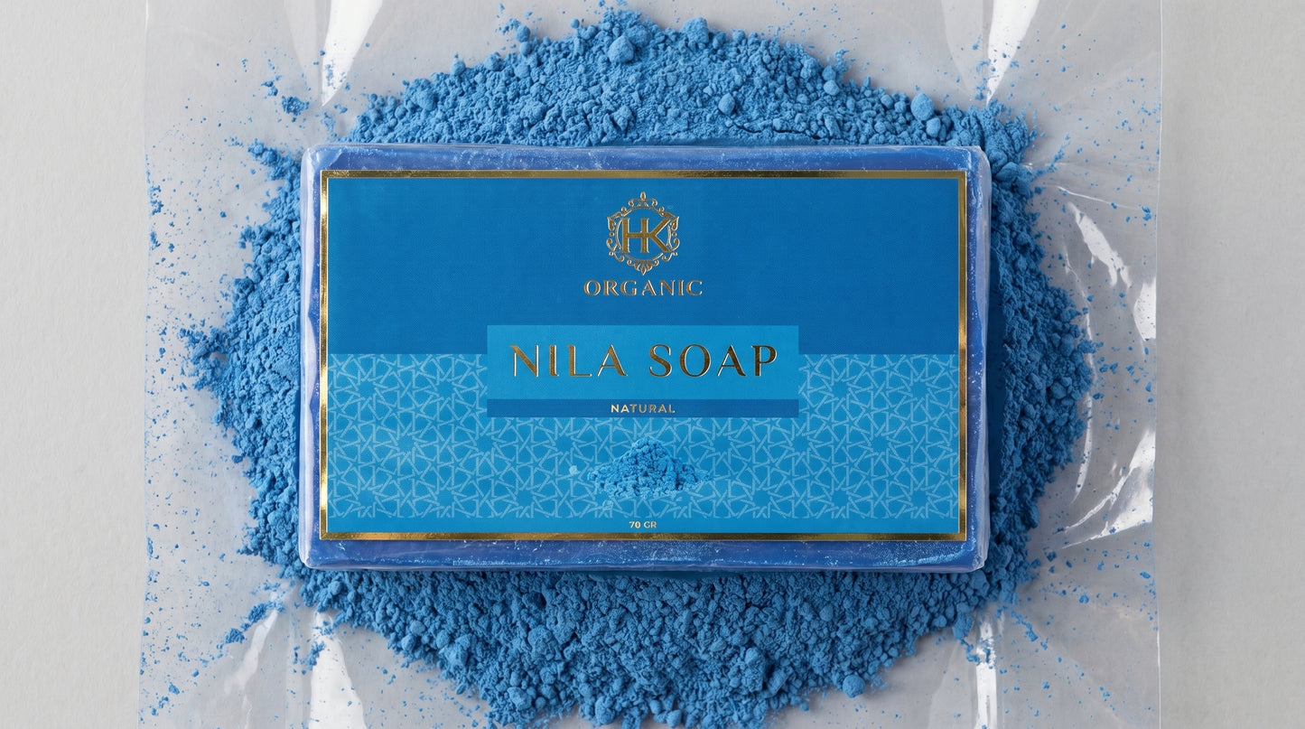 Nila Soap bar with blue packaging surrounded by blue powder on a white background