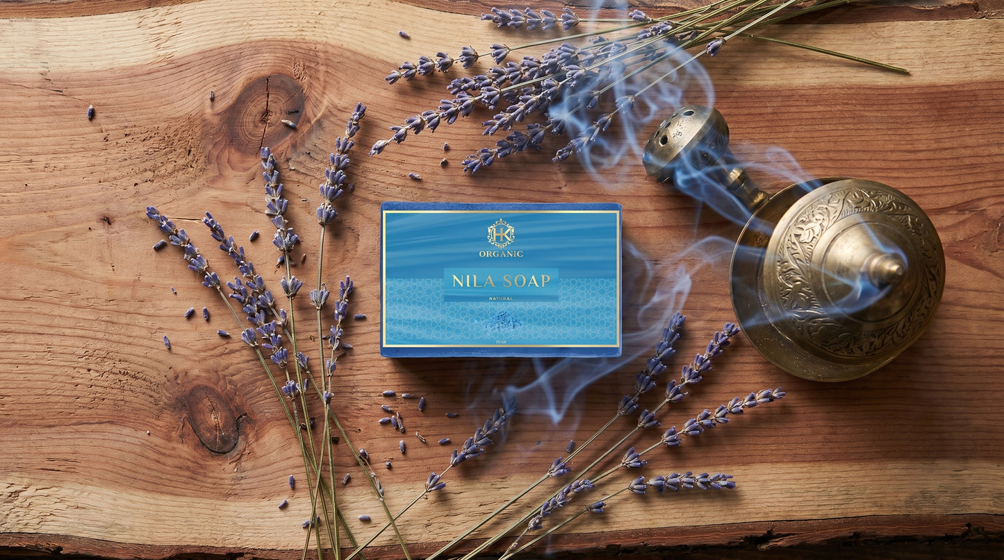 Bar of soap with a blue box surrounded by lavender flowers on a wooden surface