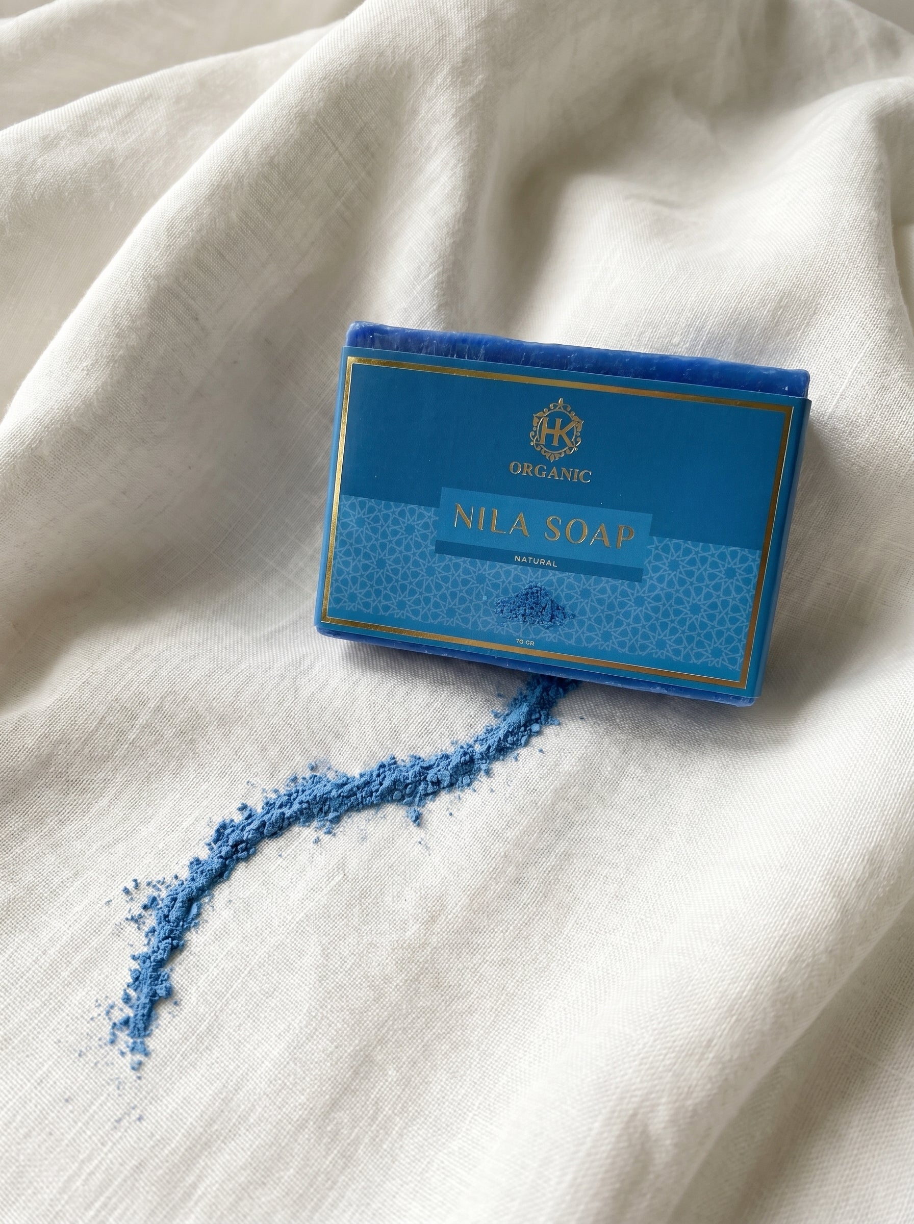 Blue soap bar with a visible brand logo on a white fabric background