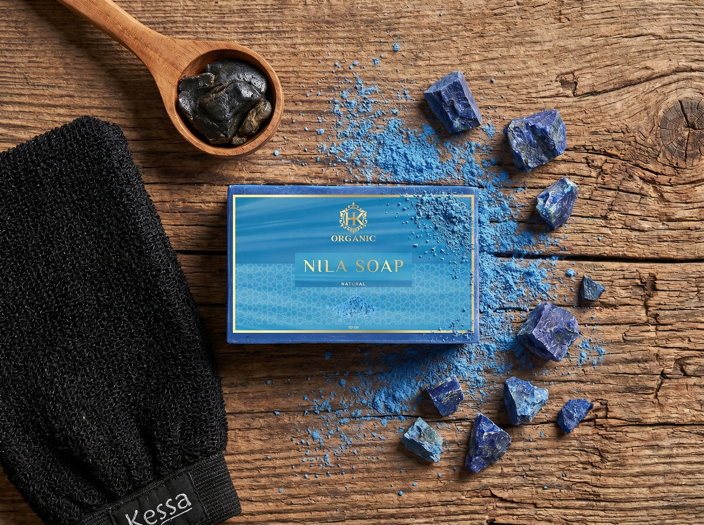 Kessa Nila Soap packaging with blue powder and black scrubber on wooden surface