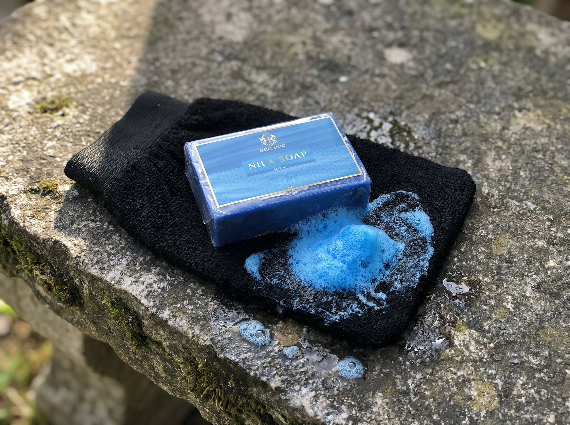 Blue bar of soap with a black towel on a stone surface