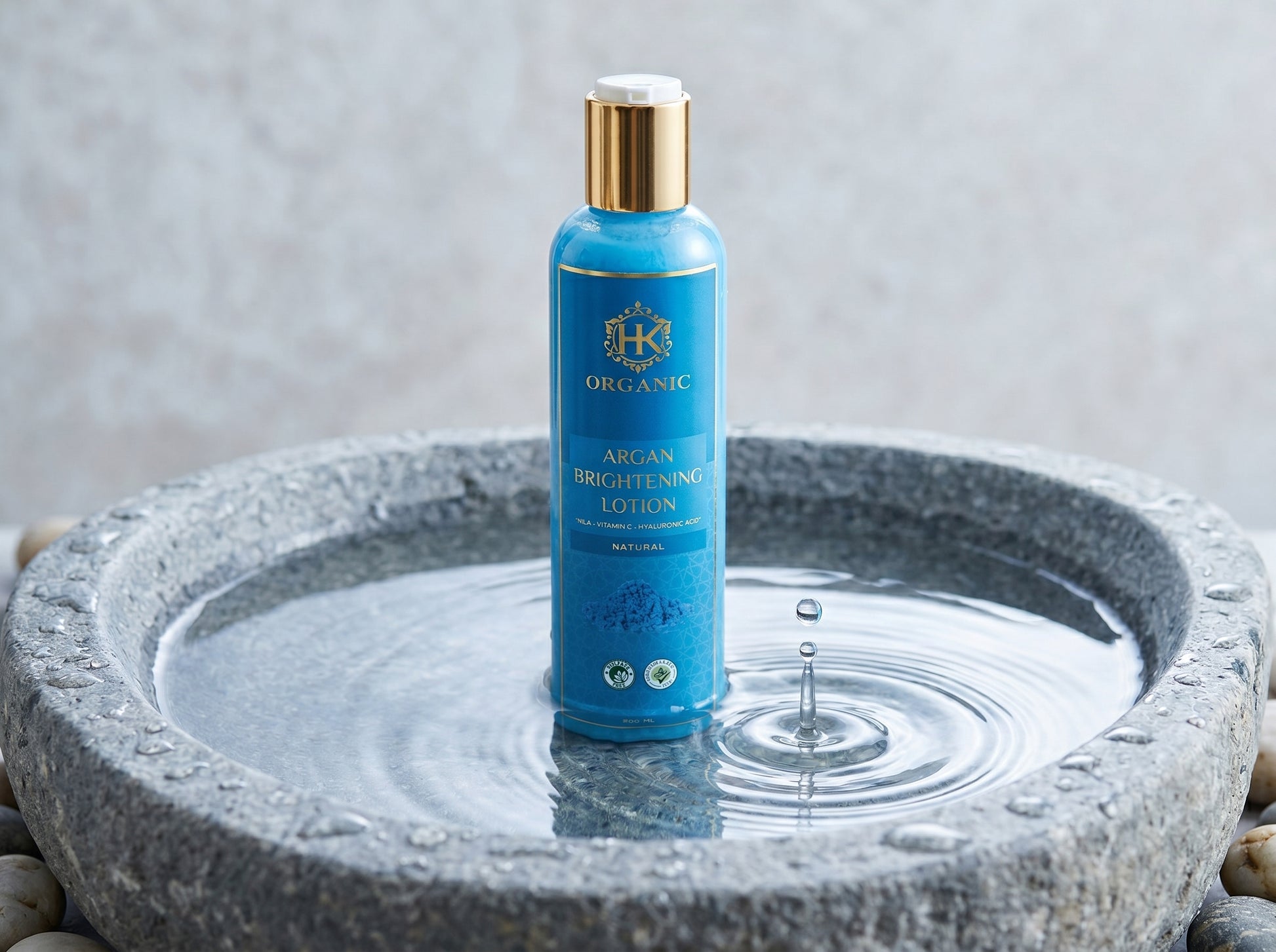 Blue bottle of organic lotion in a stone bowl with water