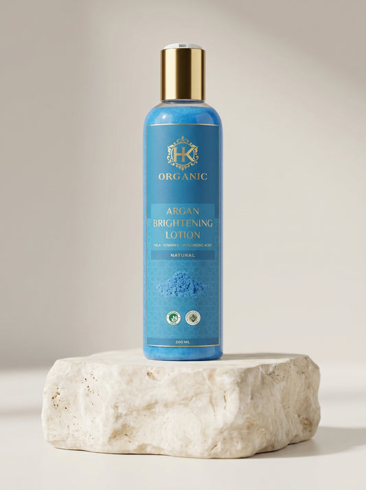 Blue bottle of organic argan brightening lotion on a stone surface with a neutral background