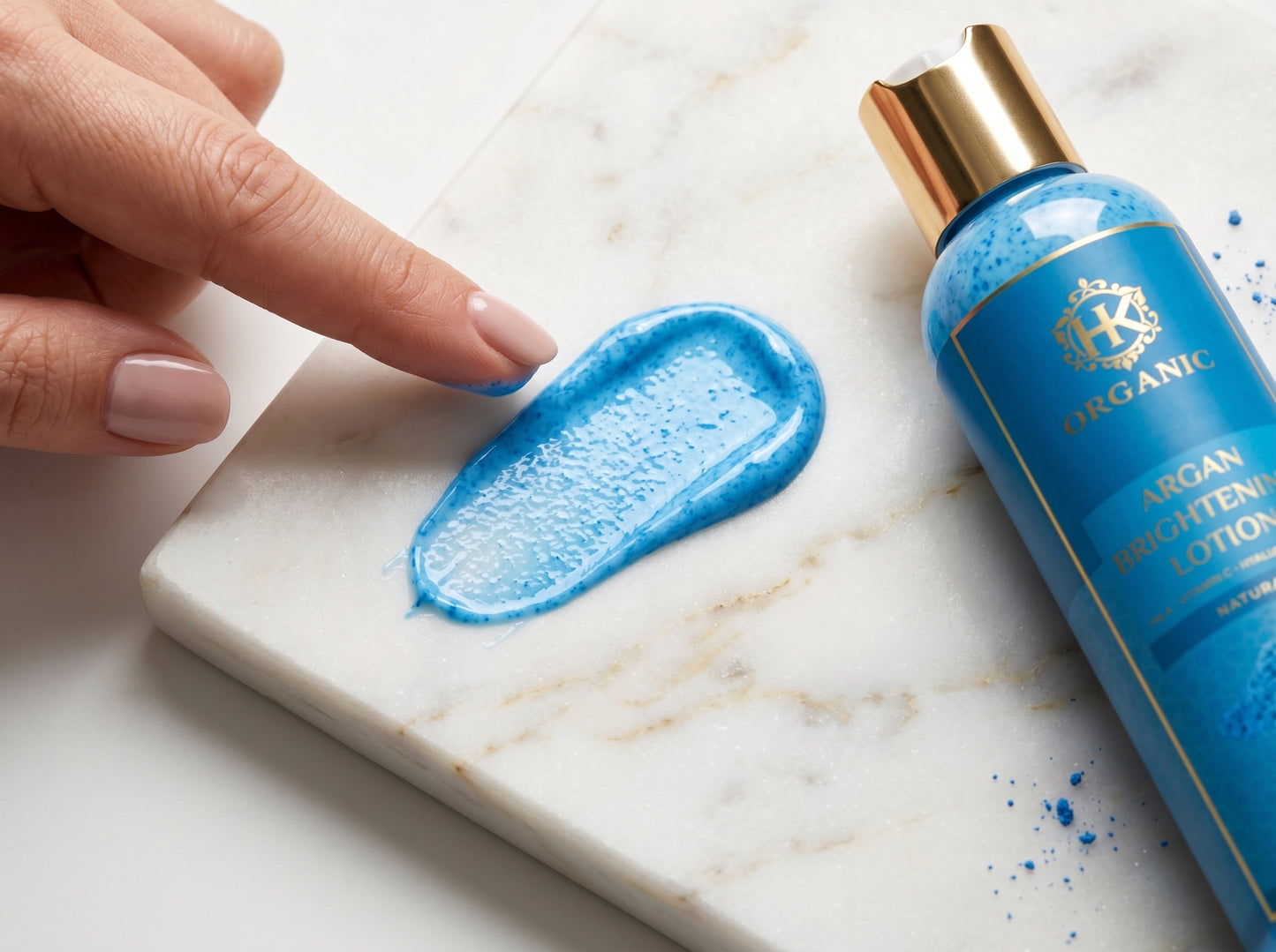 Blue lotion bottle with a hand applying blue lotion on a marble surface