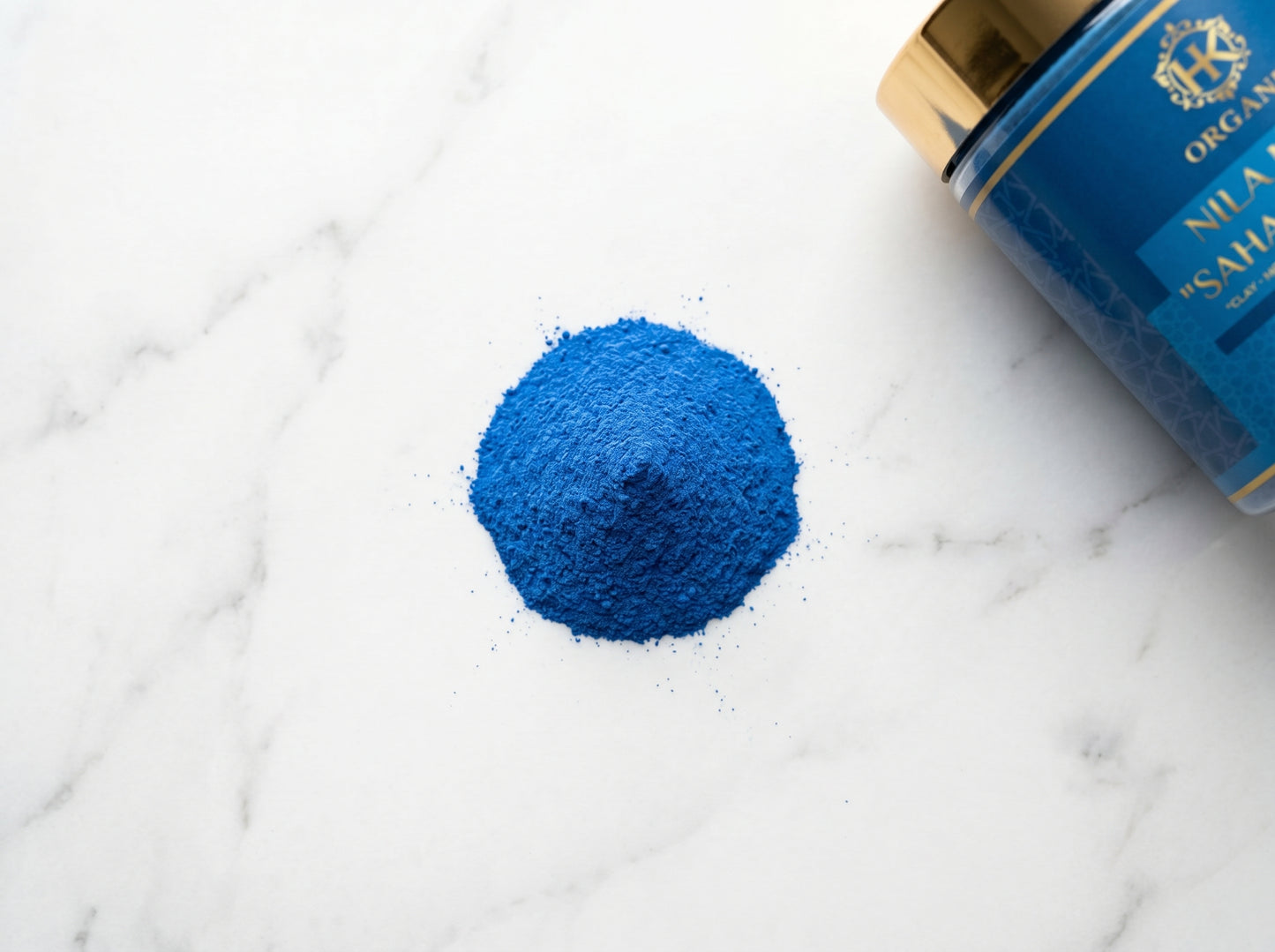 Blue powder next to a container labeled 'Nila Sahib' on a marble surface