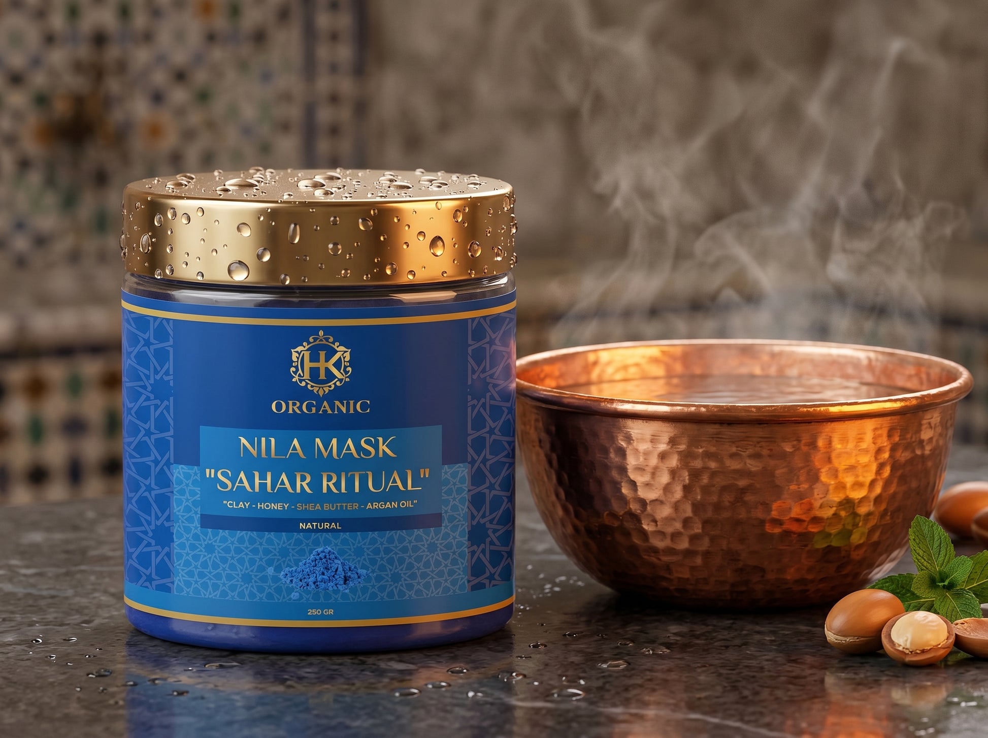 Blue jar of Nila Mask Sahar Ritual with a gold lid on a reflective surface, with a copper bowl and nuts in the background.