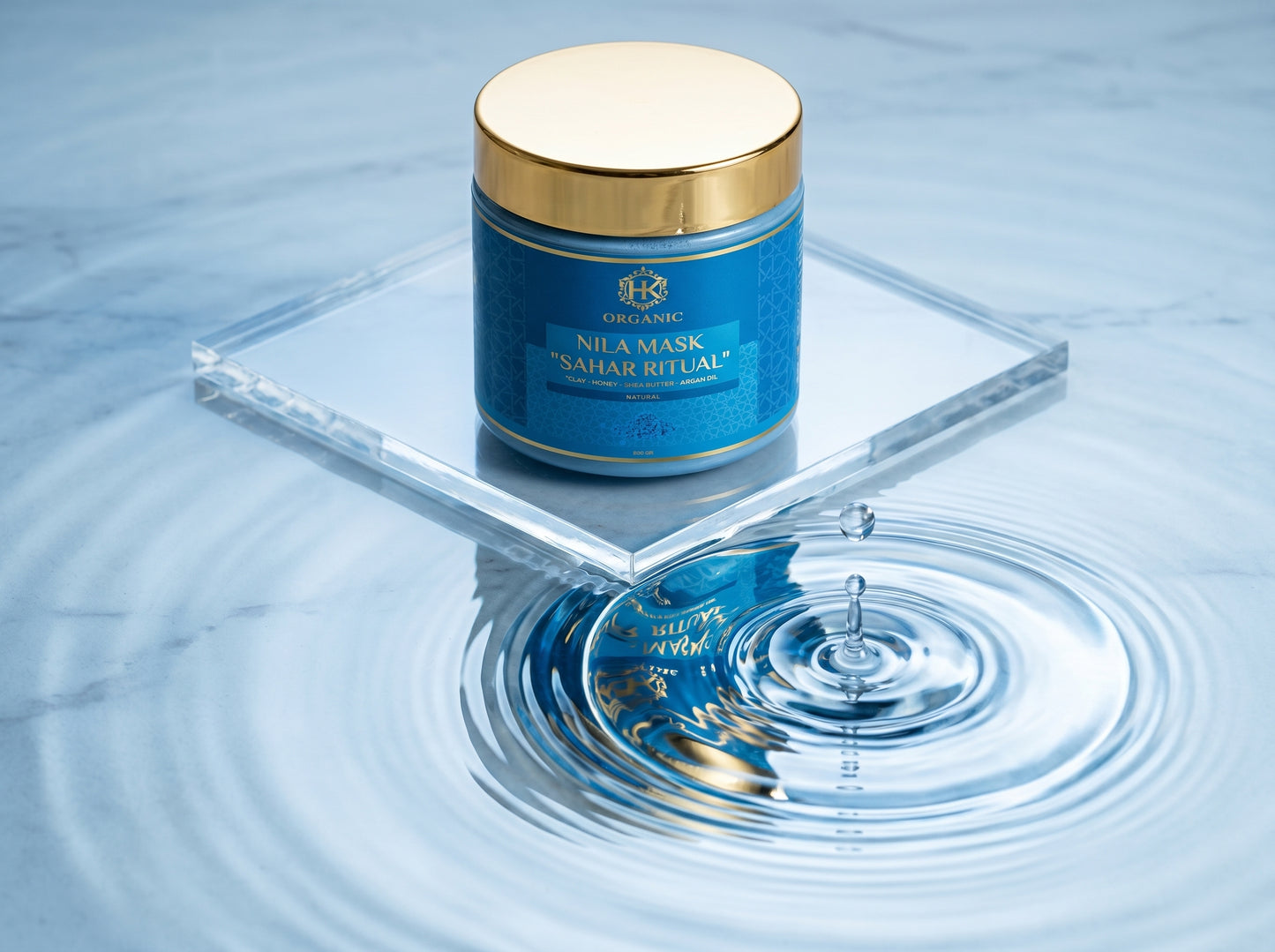 Blue skincare mask jar with gold lid on a clear stand over water