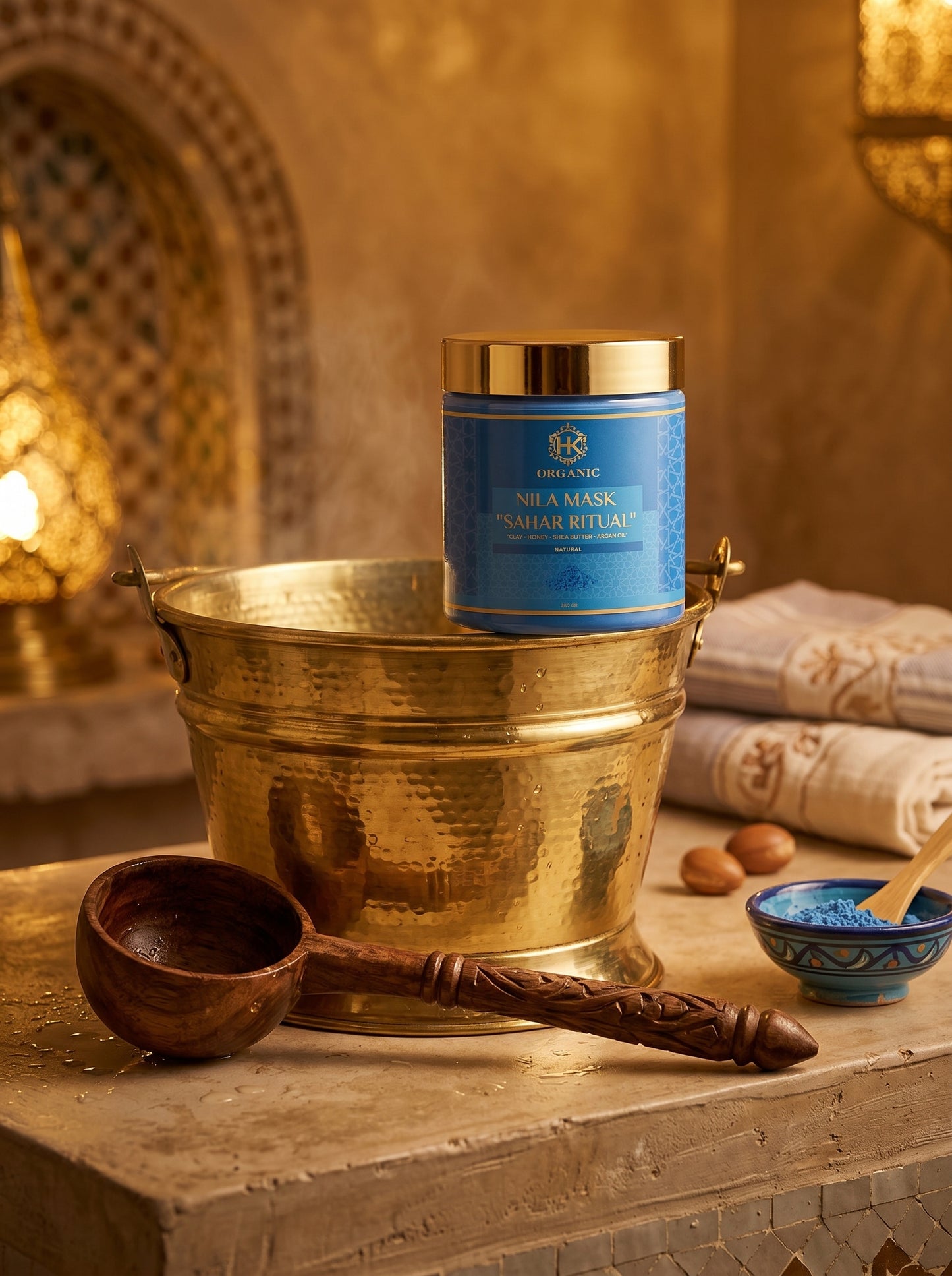 Candle in a blue container with gold lid on a stone surface with decorative elements