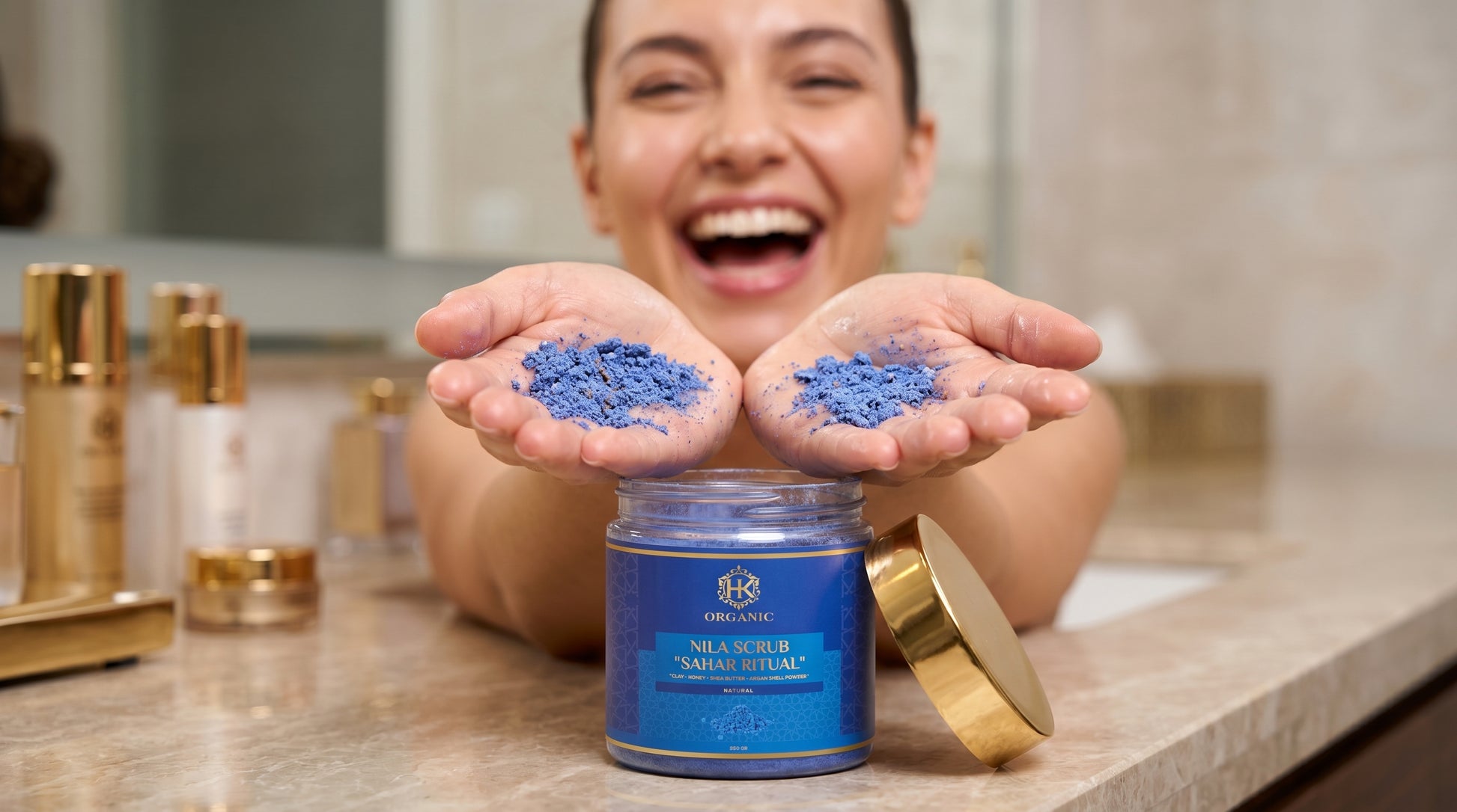 Person holding blue powder in their hands with a jar of the powder on a bathroom counter.