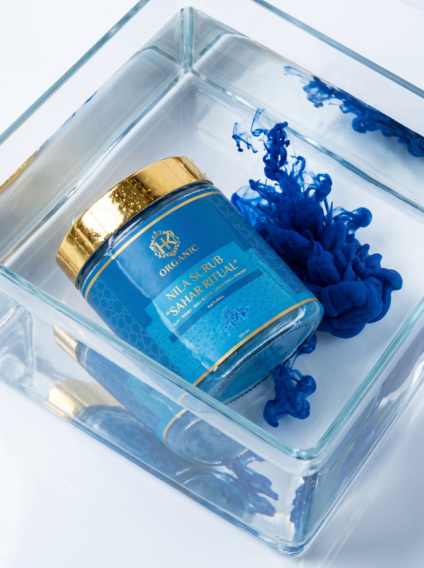 Blue skincare jar with gold cap in a clear box on a white background