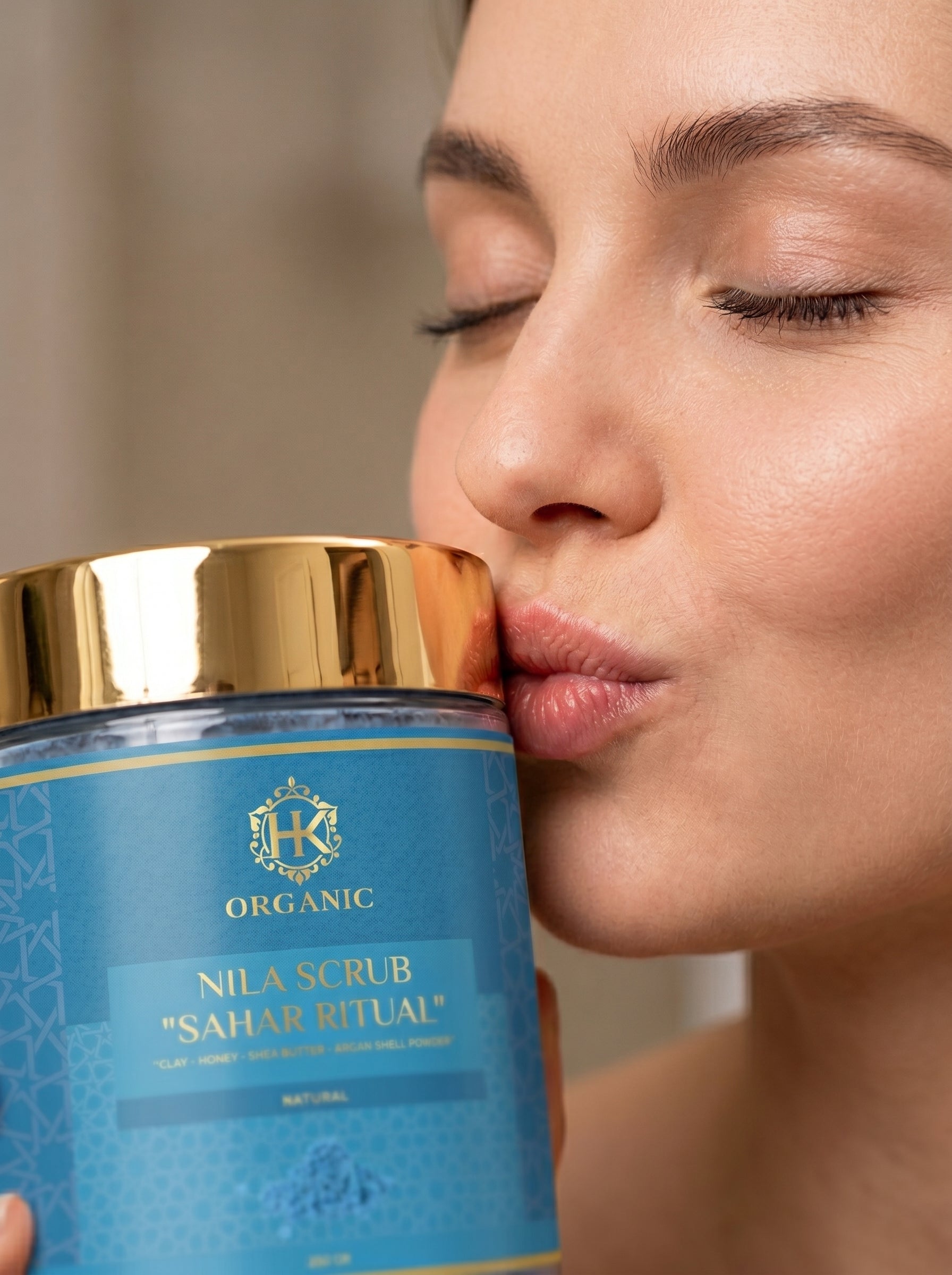 Woman kissing a blue container labeled 'Nila Scrub Sahar Ritual' with gold accents.