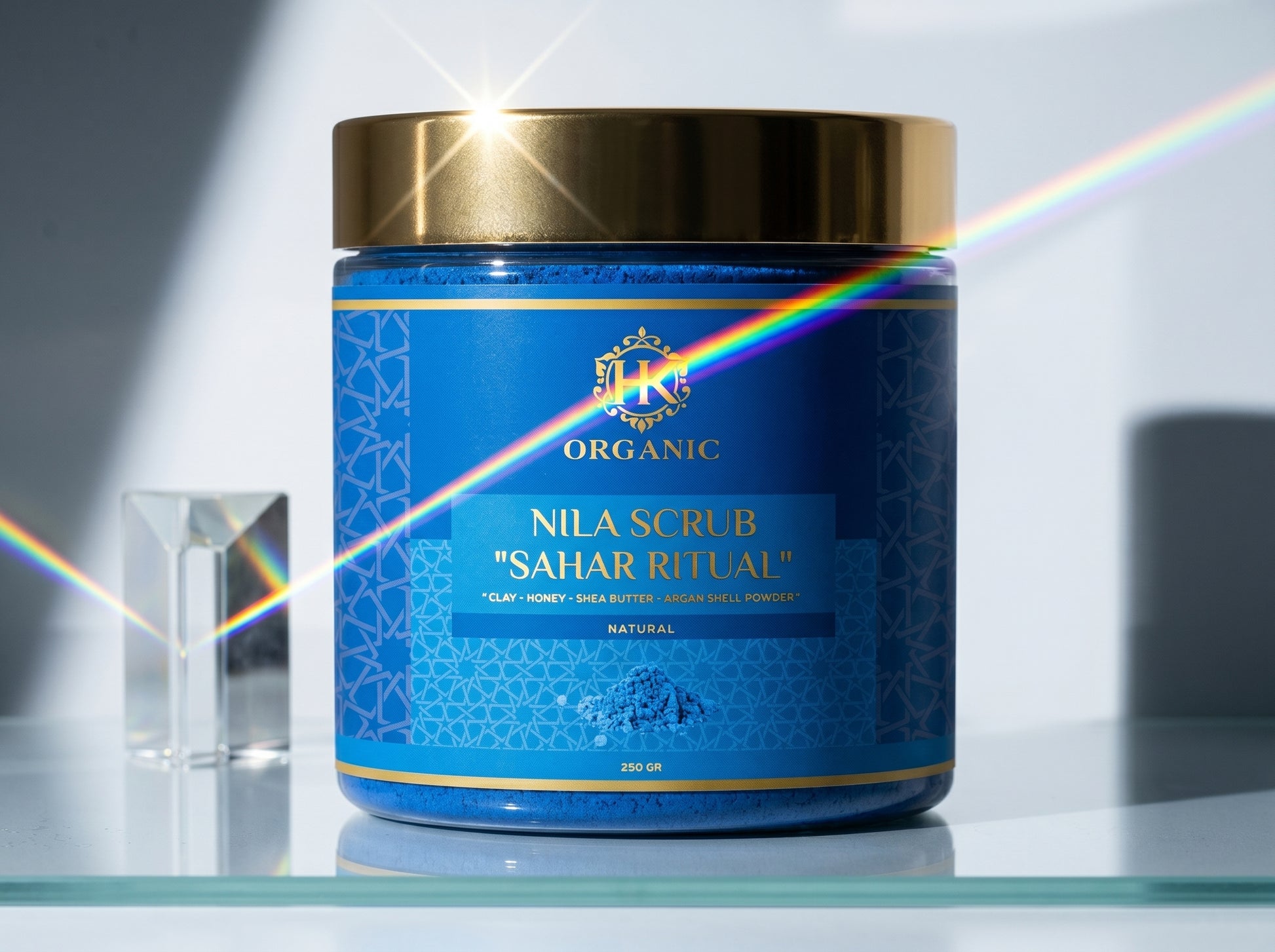 Blue jar of Nila Scrub with gold lid on a reflective surface