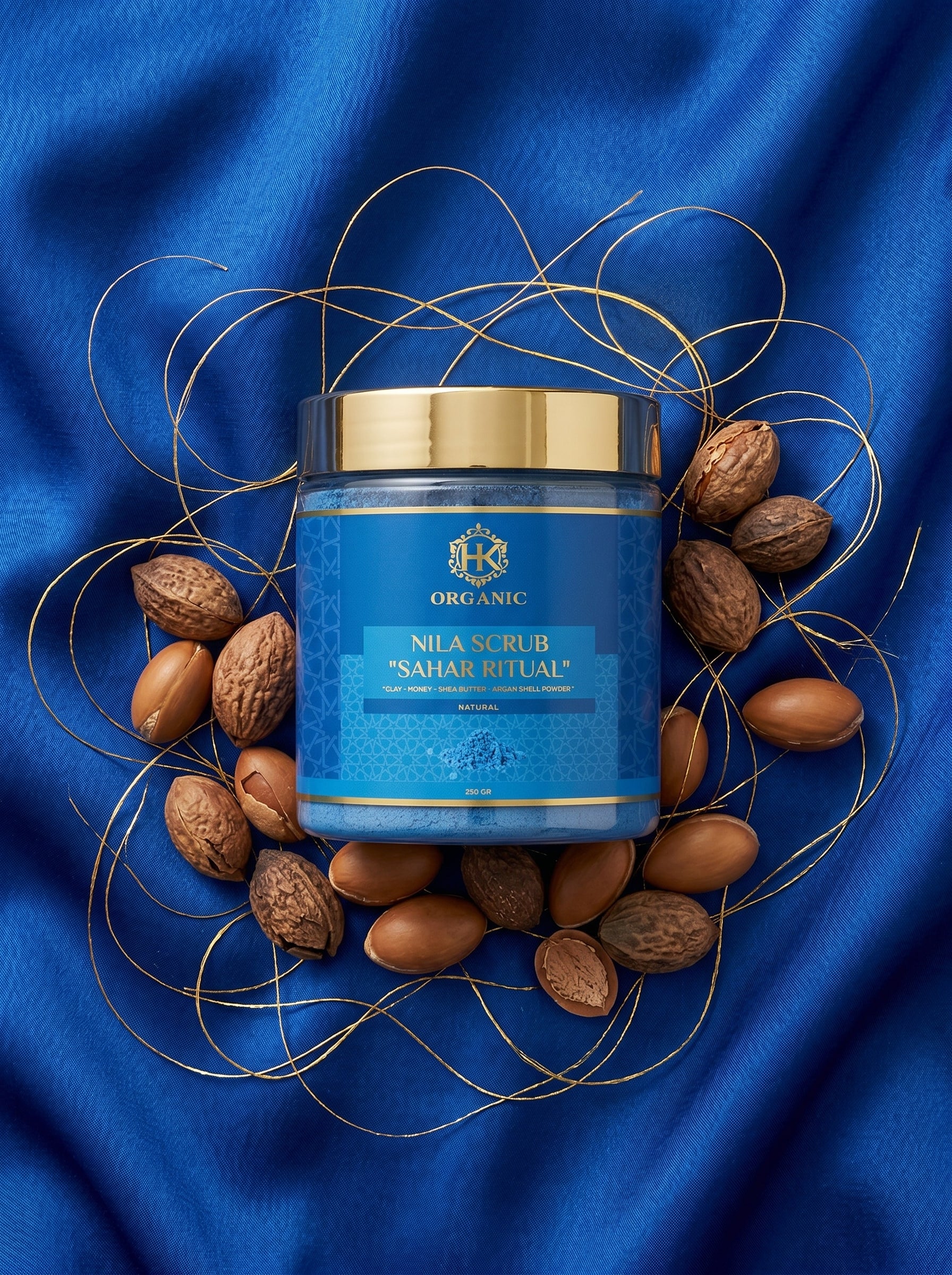 Blue jar with gold lid surrounded by almonds on a blue fabric background