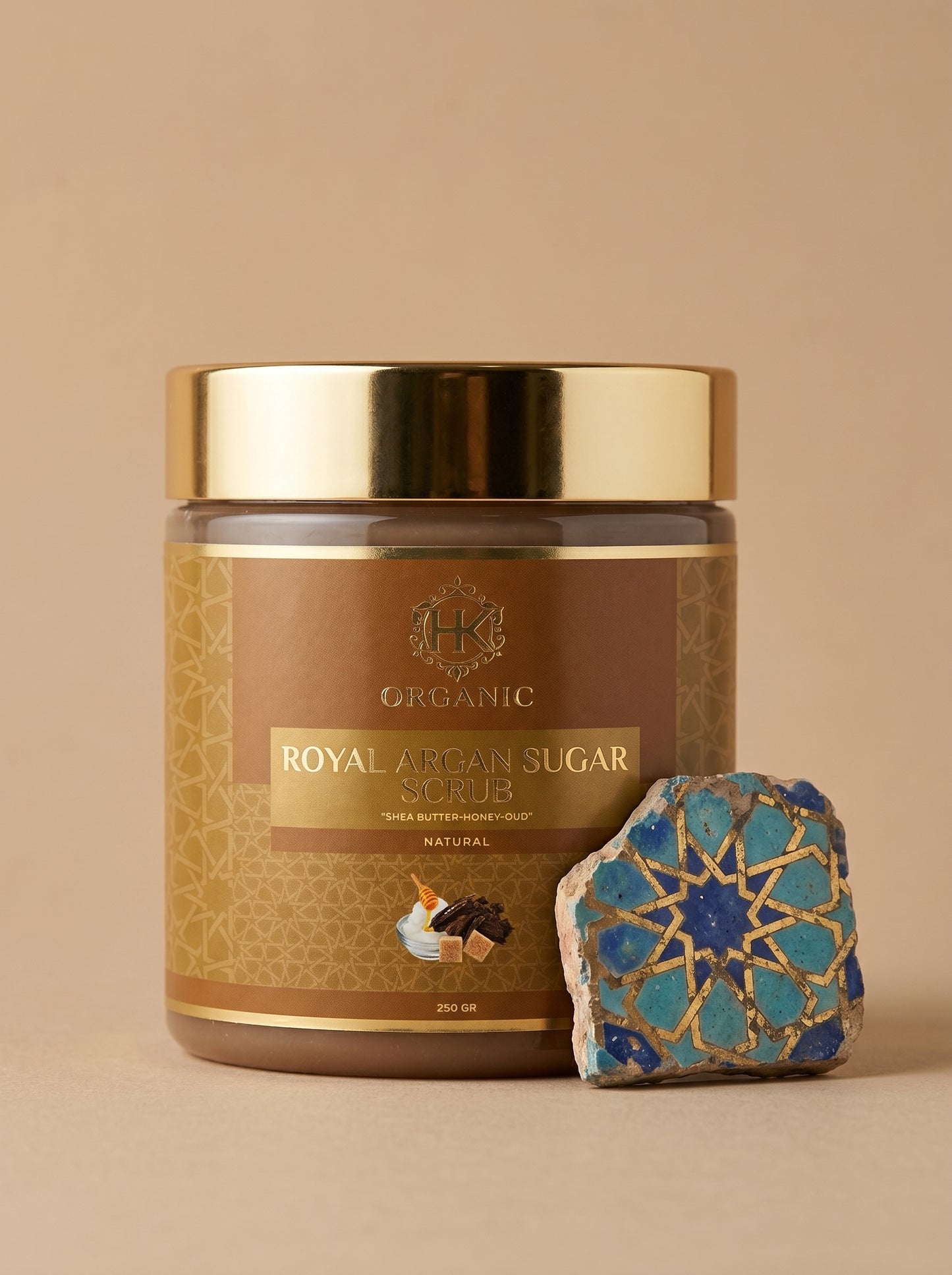 Jar of organic royal argan sugar scrub with decorative stone on a beige background