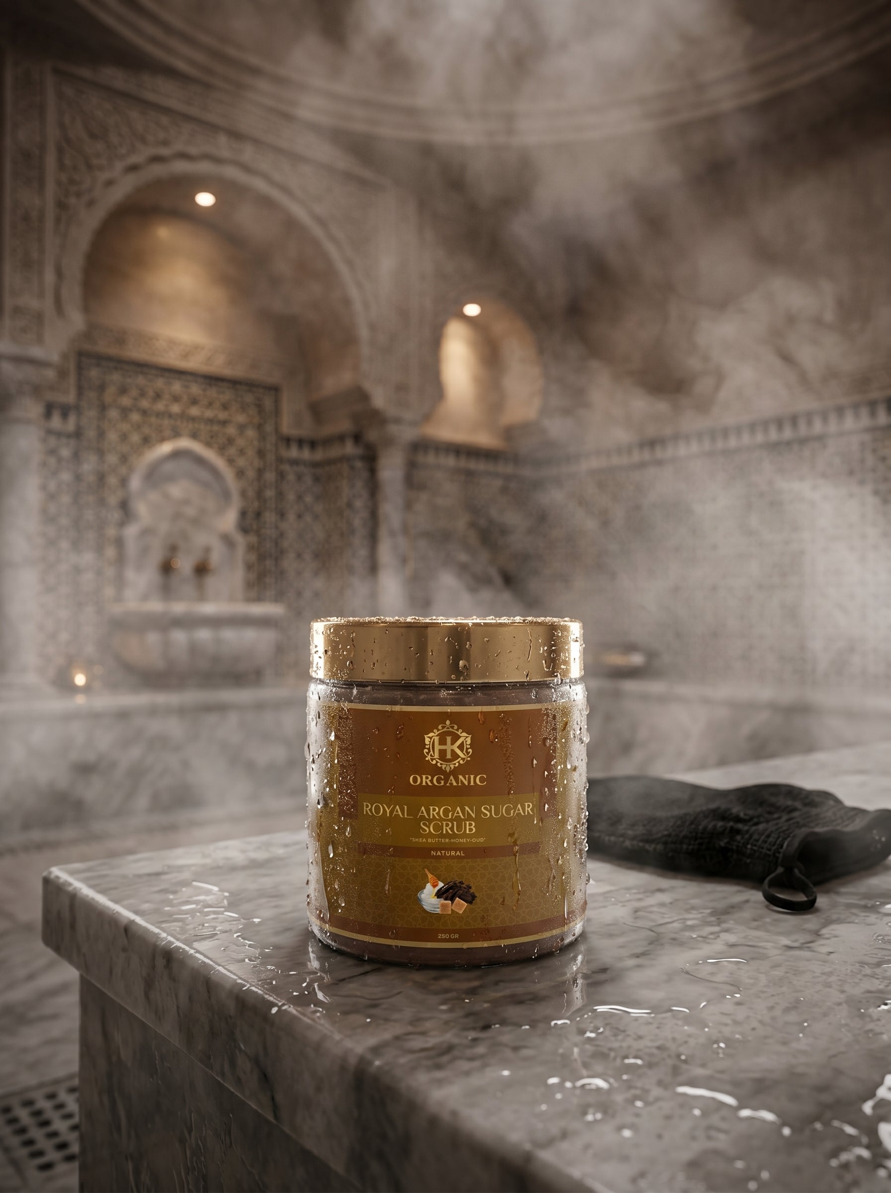 Jar of organic Royal Argan Sugar Scrub on a stone surface with steamy background