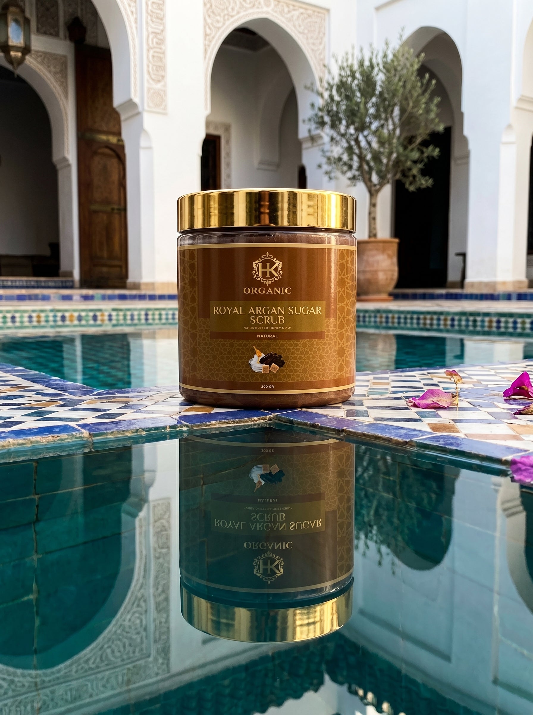 Jar of Royal Argan Sugar Scrub by HK Organic on a poolside with architectural elements in the background