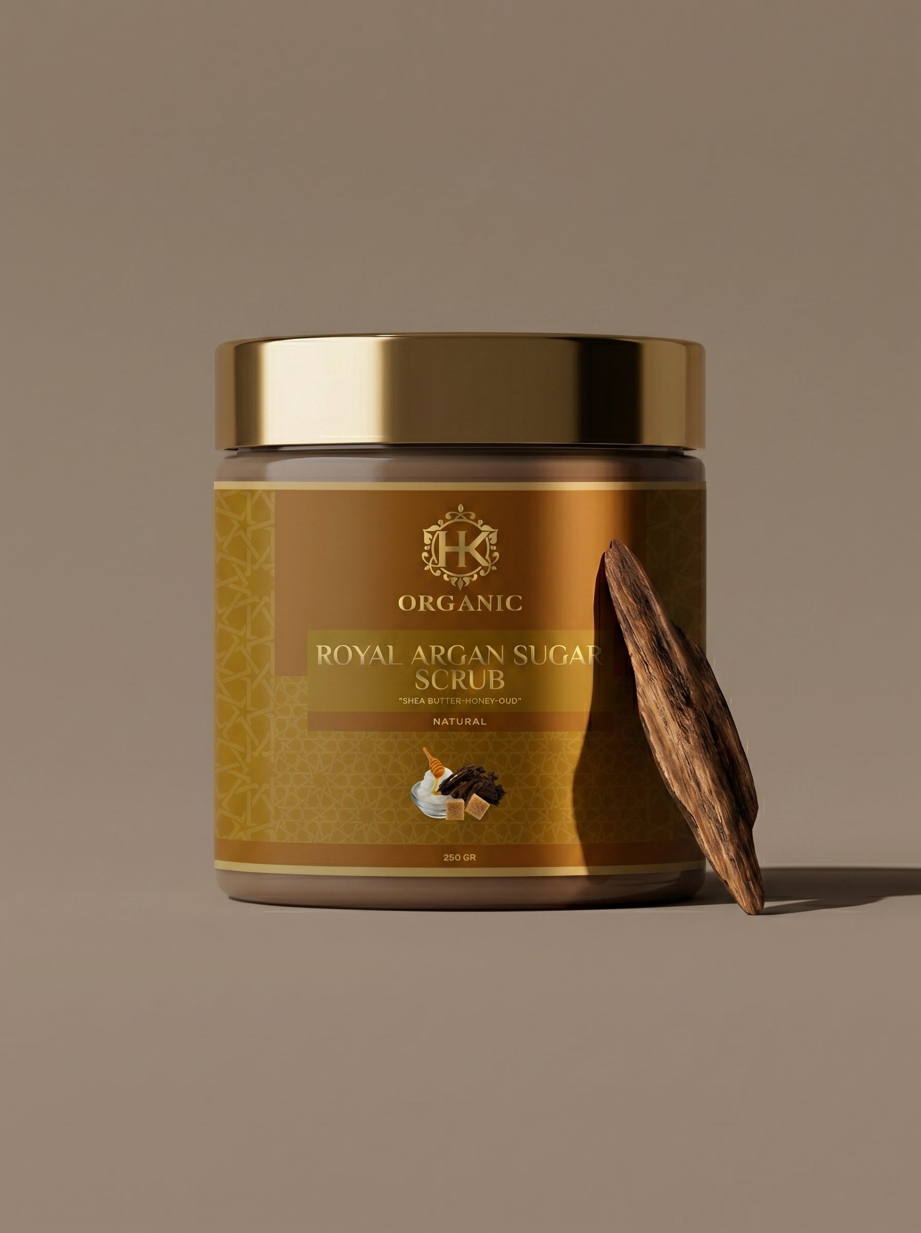 Jar of organic royal argan sugar scrub with a gold lid on a brown background