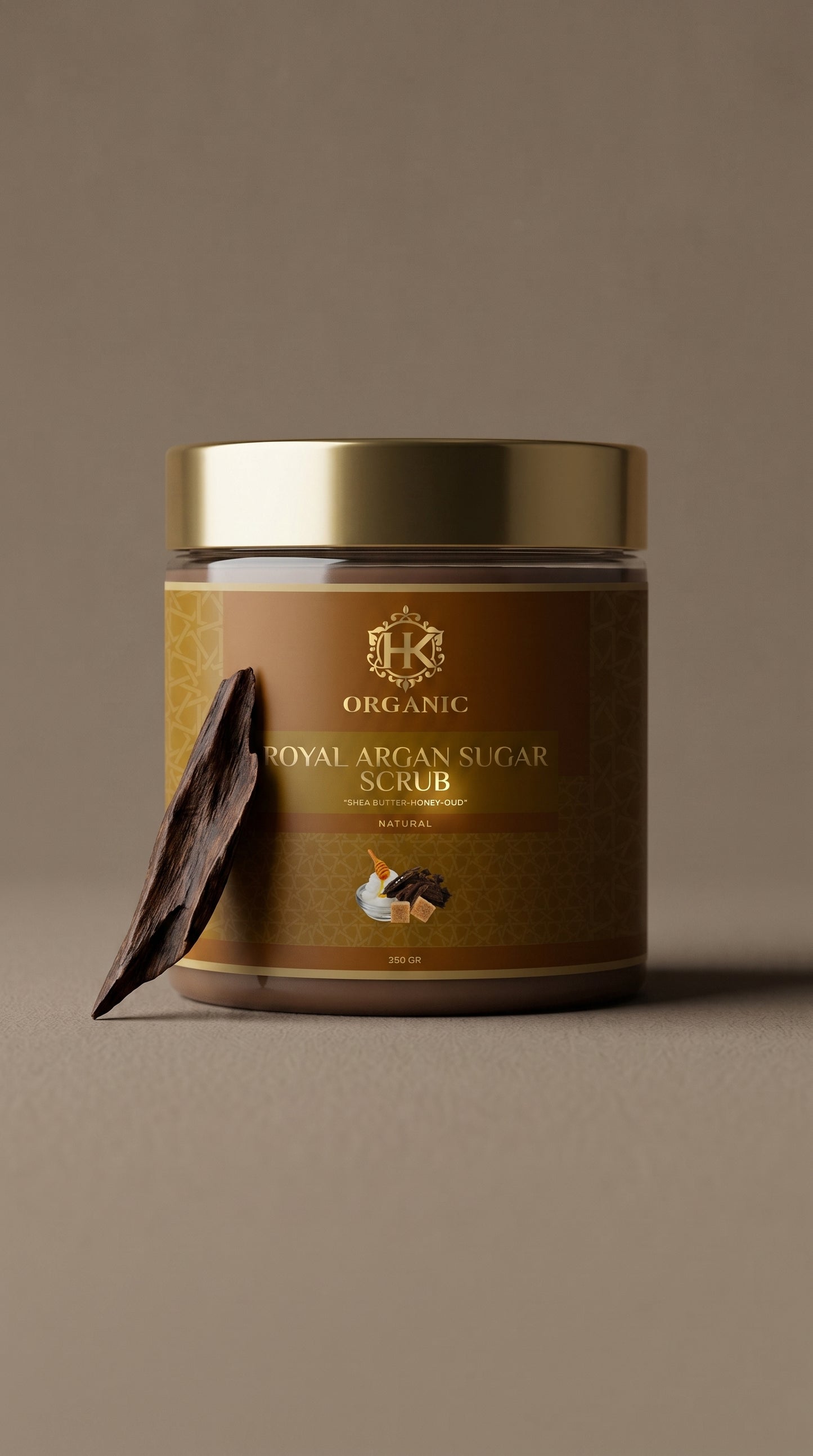 Jar of organic royal argan sugar scrub with a gold lid on a brown background