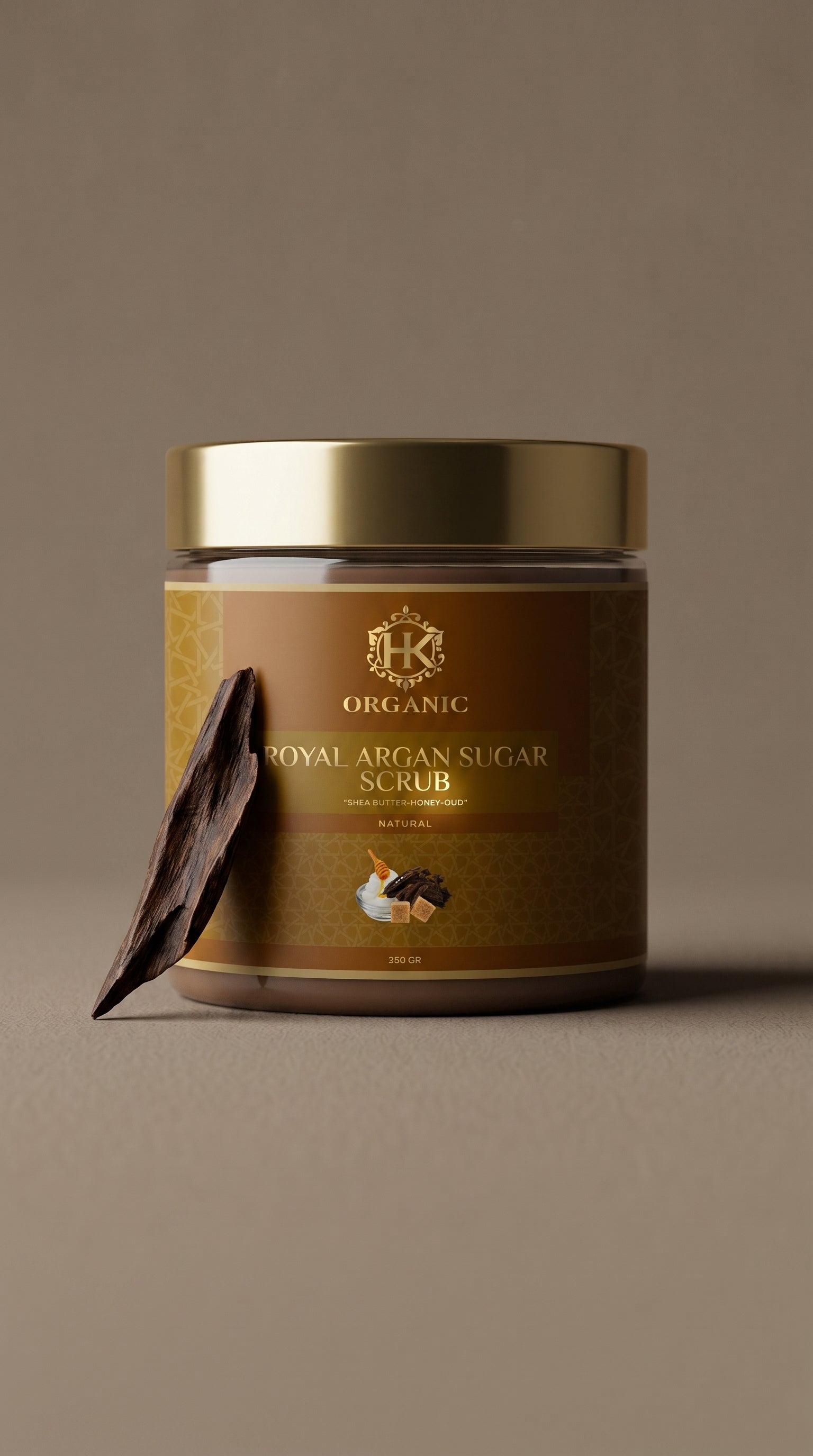 Jar of organic royal argan sugar scrub with a gold lid on a brown background
