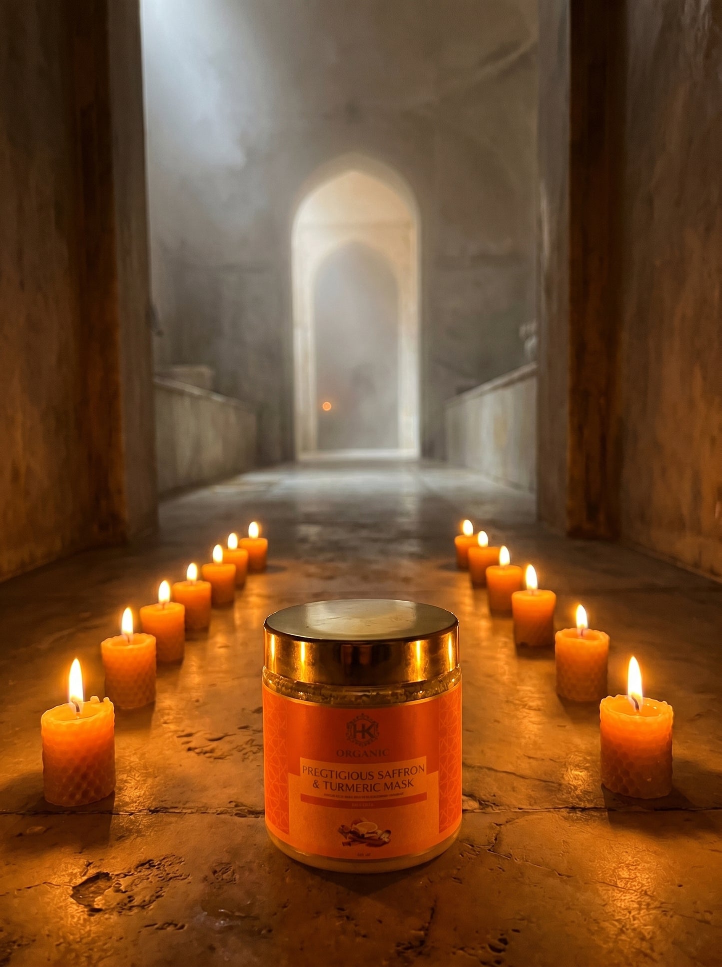 turmeric with a gold lid and orange label in a dimly lit room with candles.