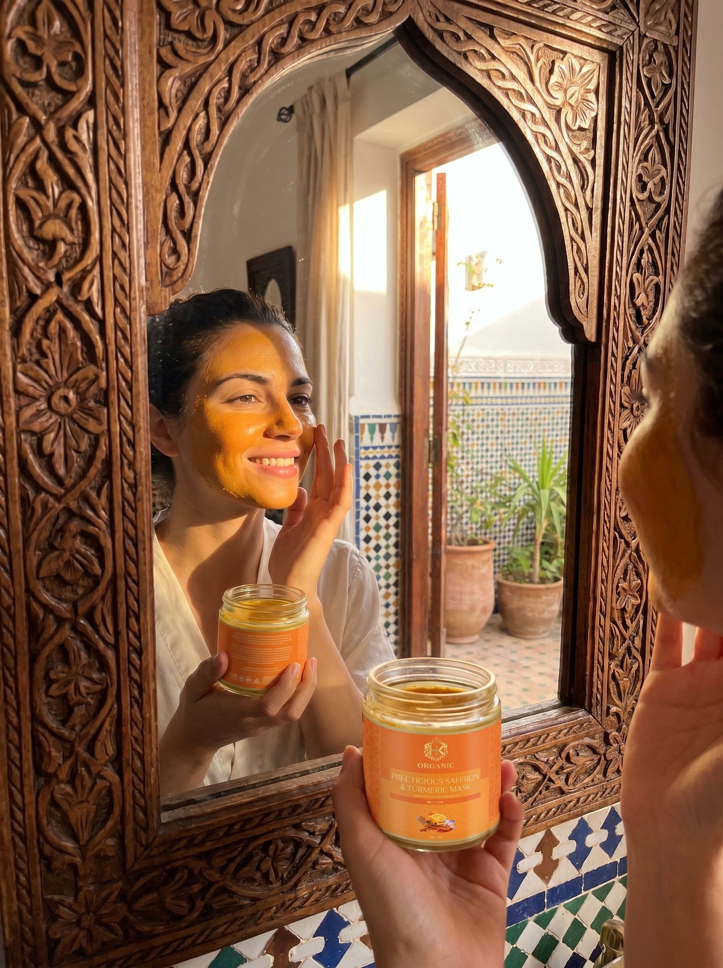 Person holding a jar of skincare product with turmeric  in front of an ornate mirror.