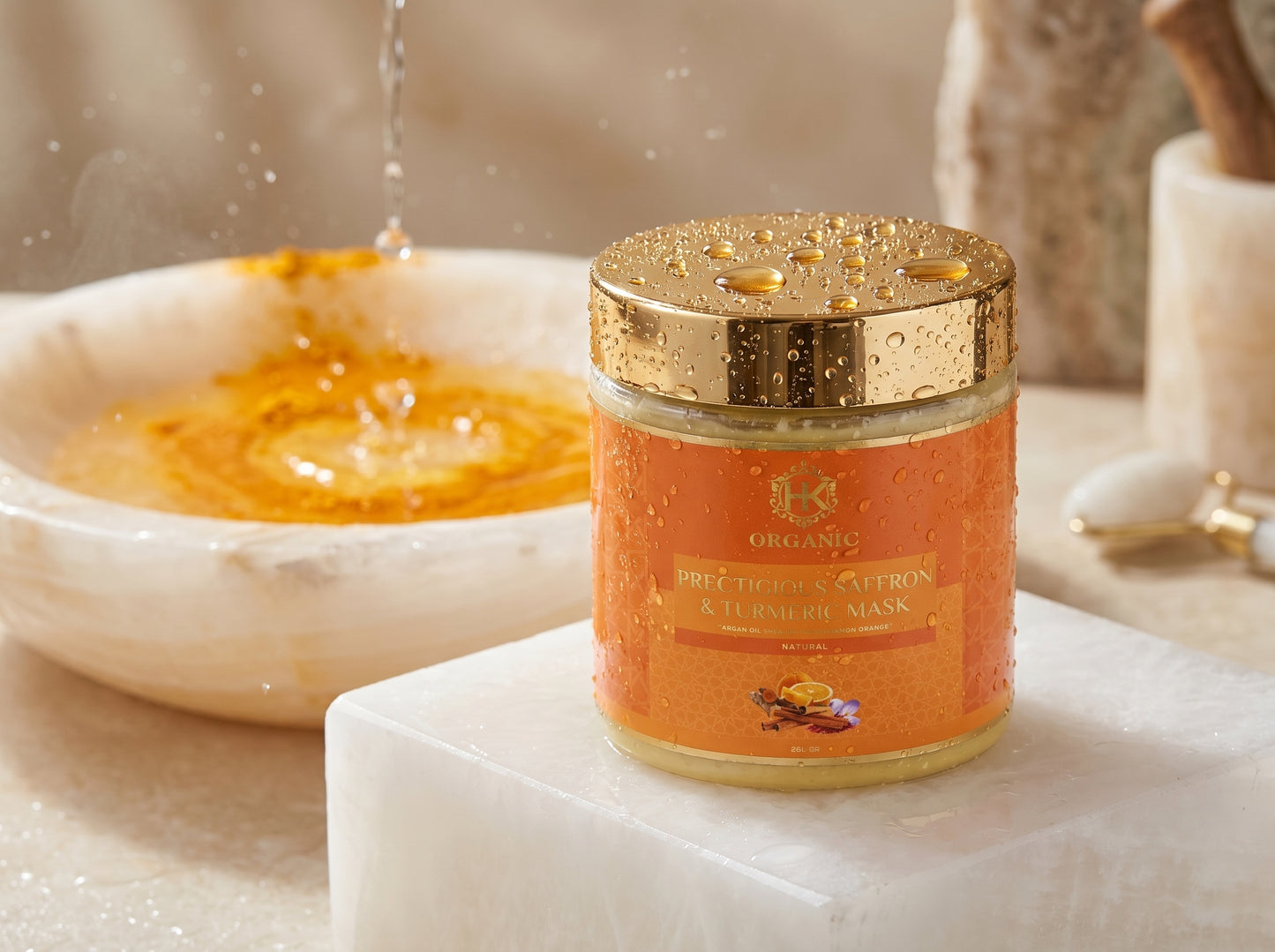 Jar of turmeric on a marble surface with a bowl of honey in the background