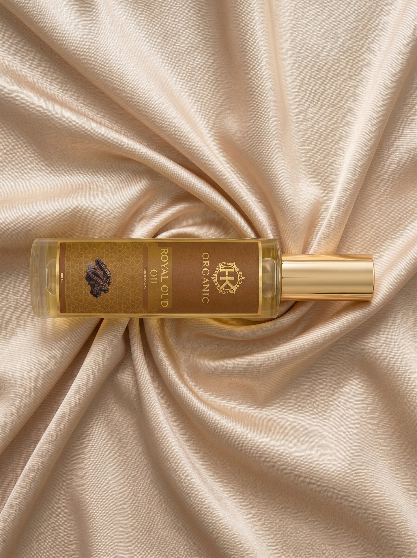 Gold bottle of organic royal oil on a beige satin background