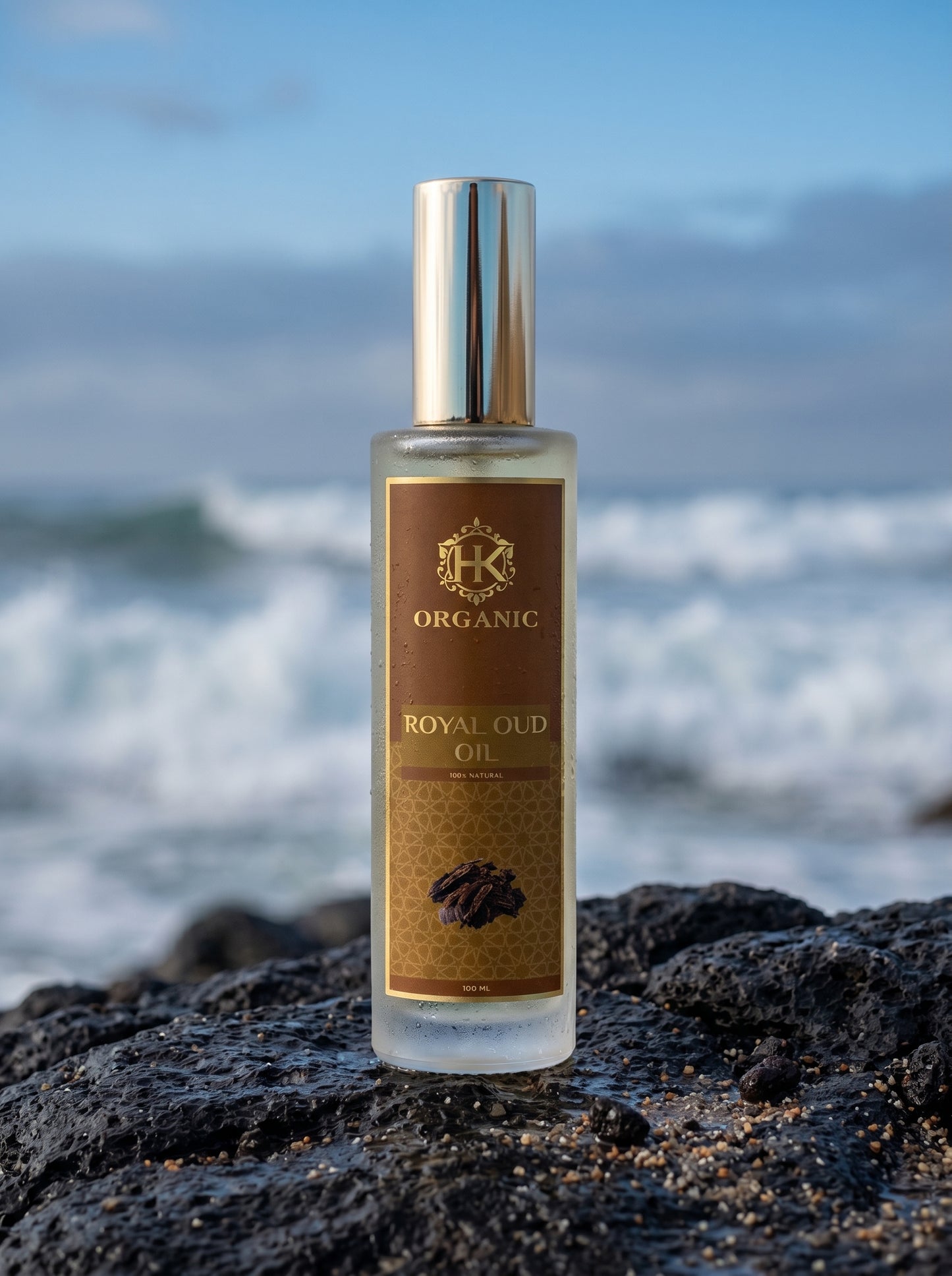 Bottle of Royal Oud Oil on a rocky beach with ocean waves in the background