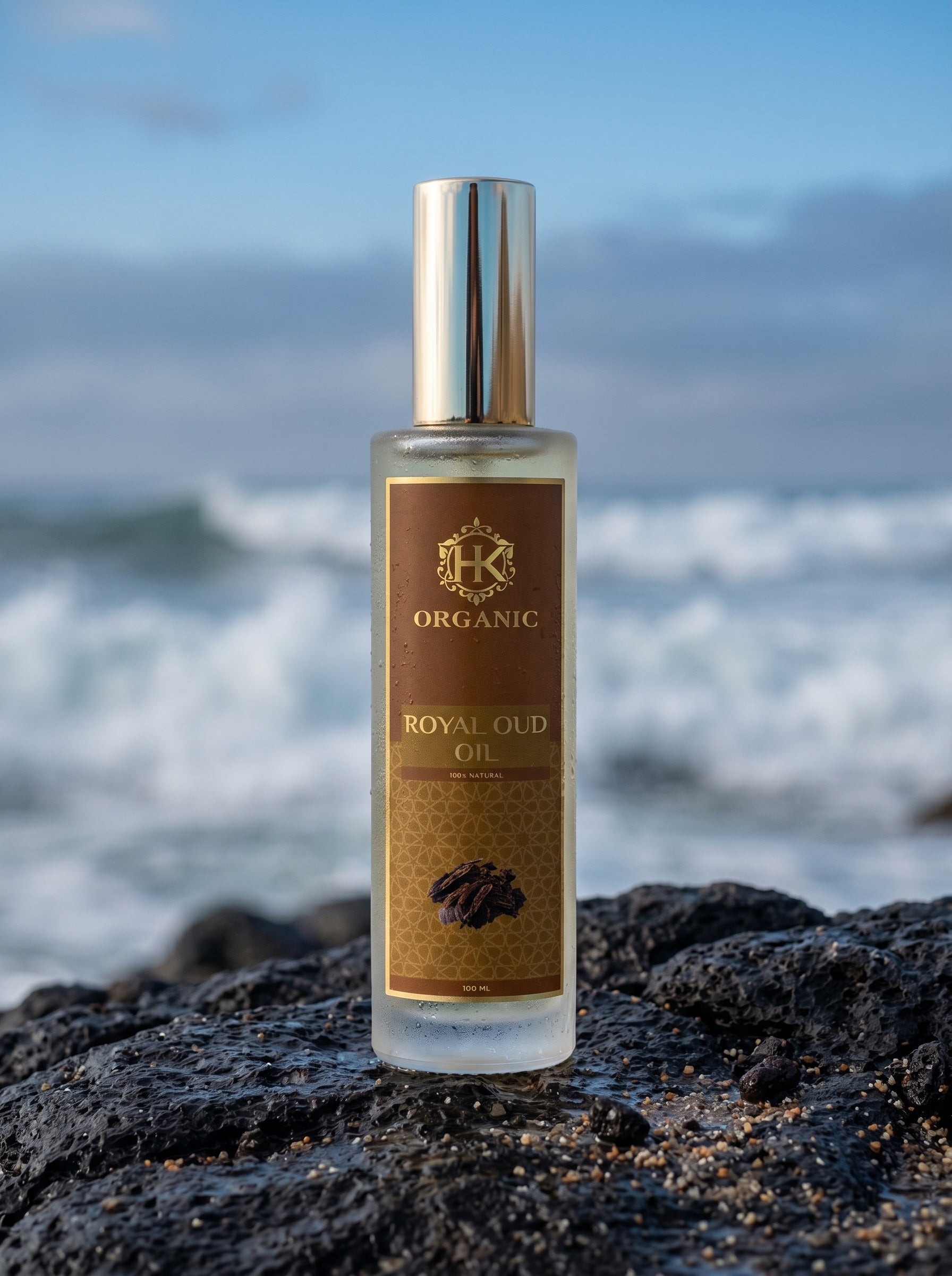 Bottle of Royal Oud Oil on a rocky beach with ocean waves in the background