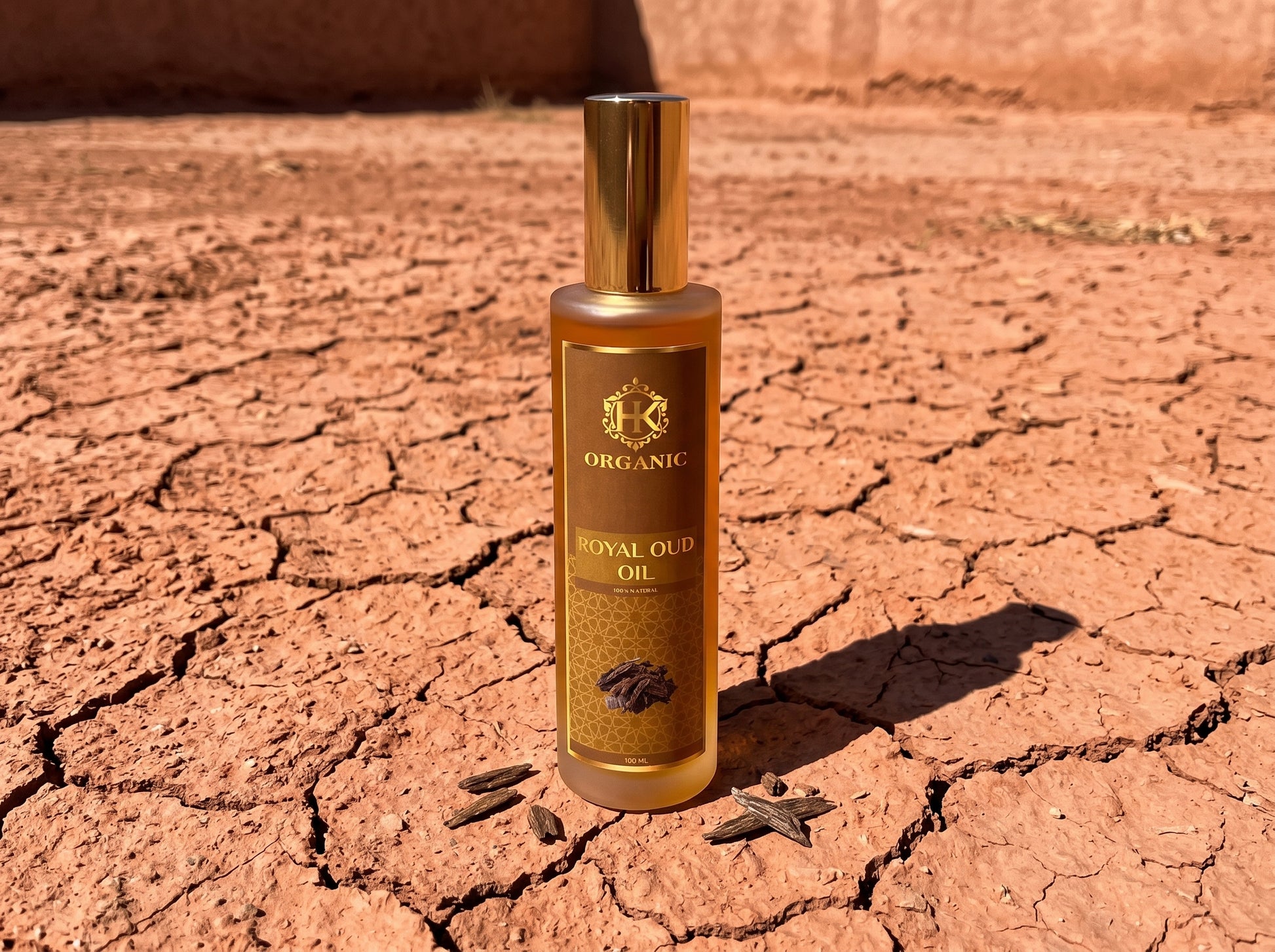 Bottle of organic royal oud oil on a cracked desert floor