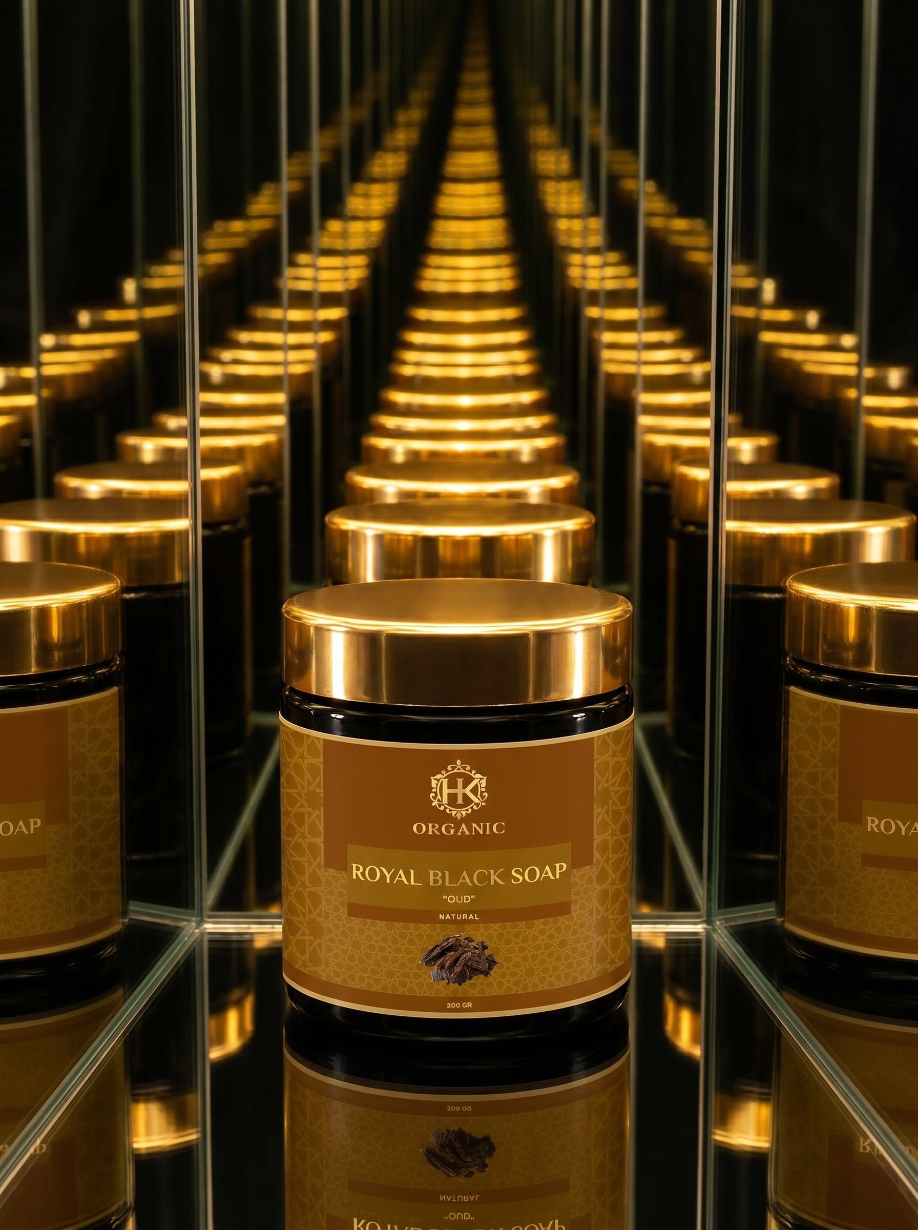 Row of Royal Black Soap jars with gold lids on a reflective surface.