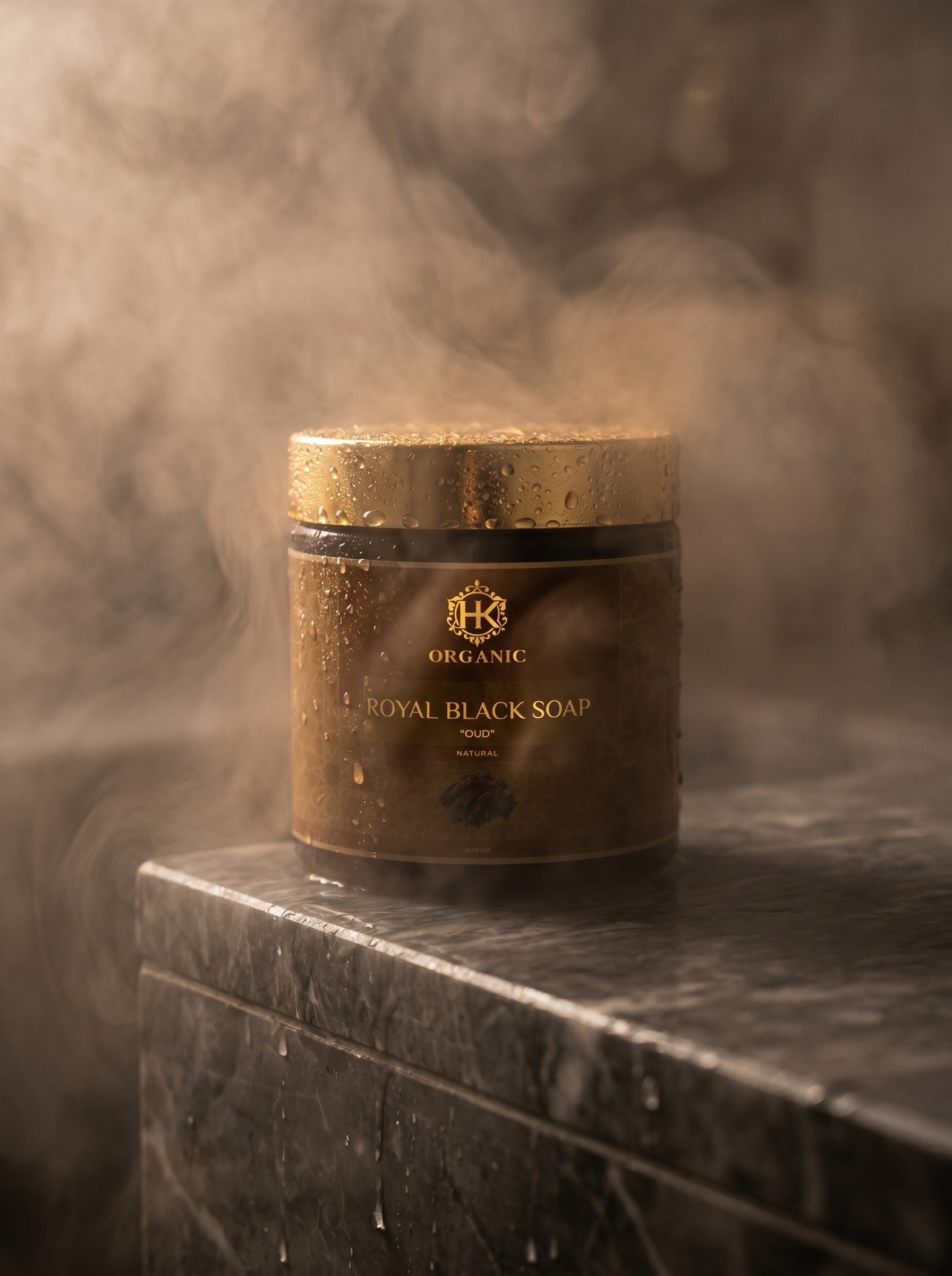 Jar of Royal Black Soap with a gold lid on a marble surface, surrounded by smoke.